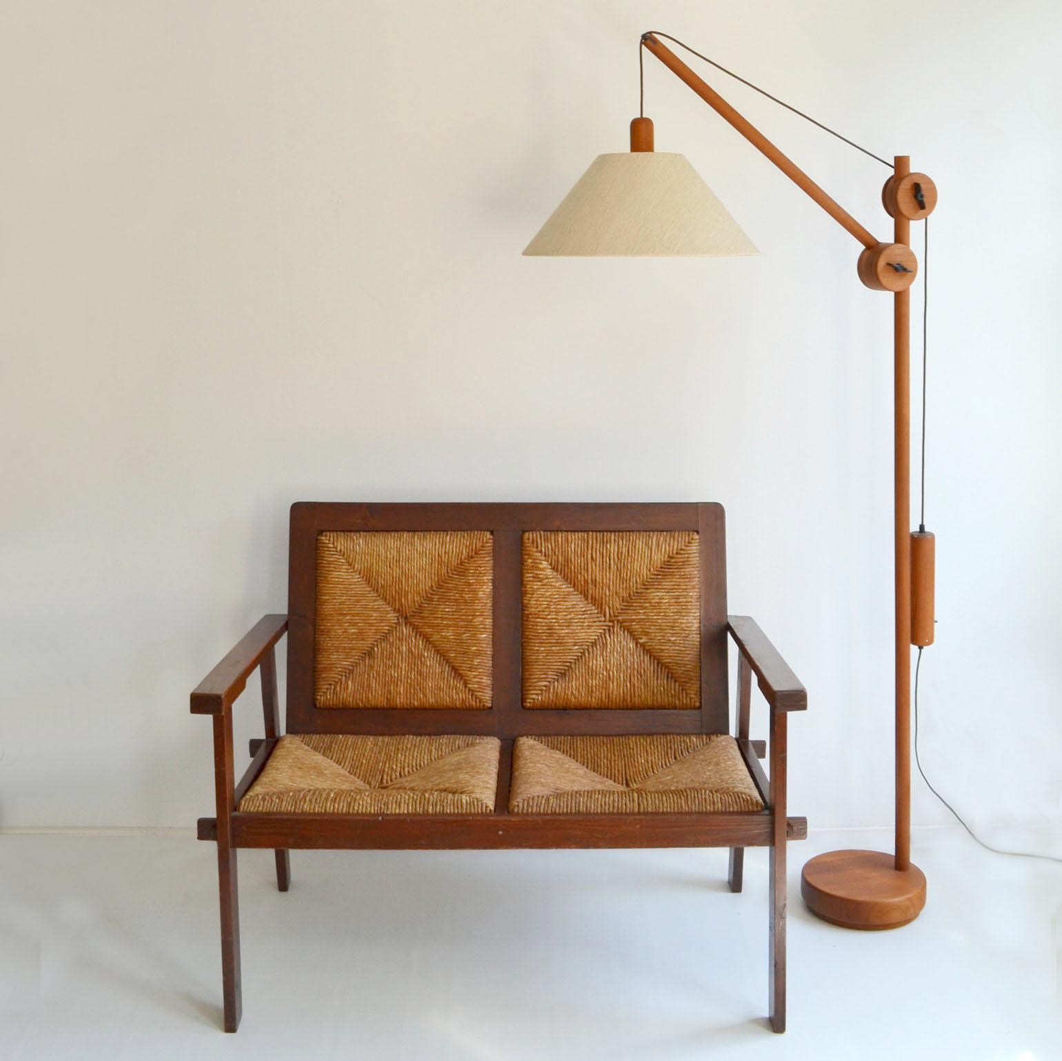 Unique Danish Mid-Century Modern floor lamp, produced around the early 1970's. The teak frame has an adjustable arm and counterbalance weight for positioning of the light source. The lamp and counterweight move in opposite directions (both away from