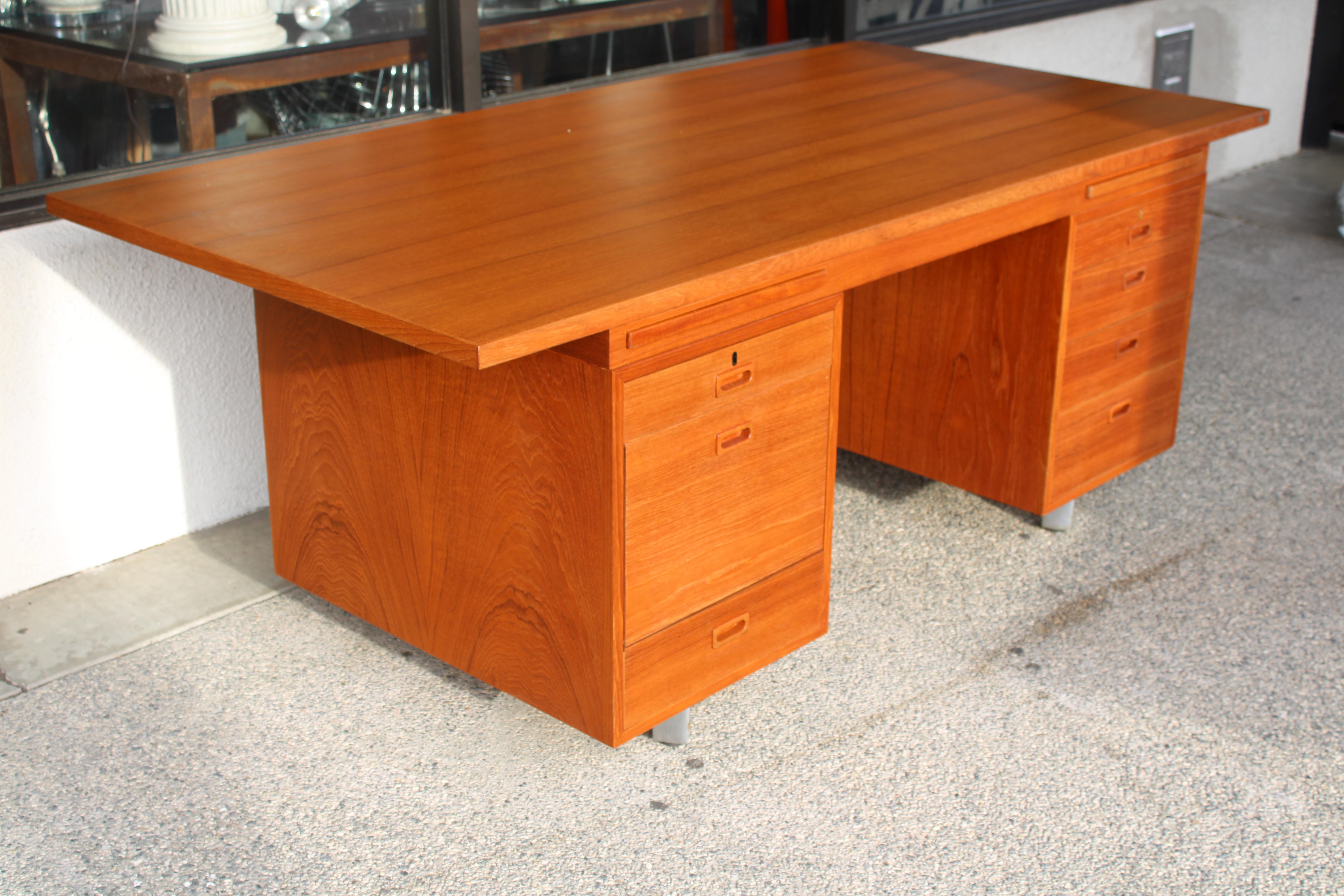 Danish teak desk manufactured by Nipu, having a rectangular top, above the seven drawer case, and rising on chrome legs. Desk has been professionally refinished. A lock with key is present and the locking mechanism does work on both drawers. The