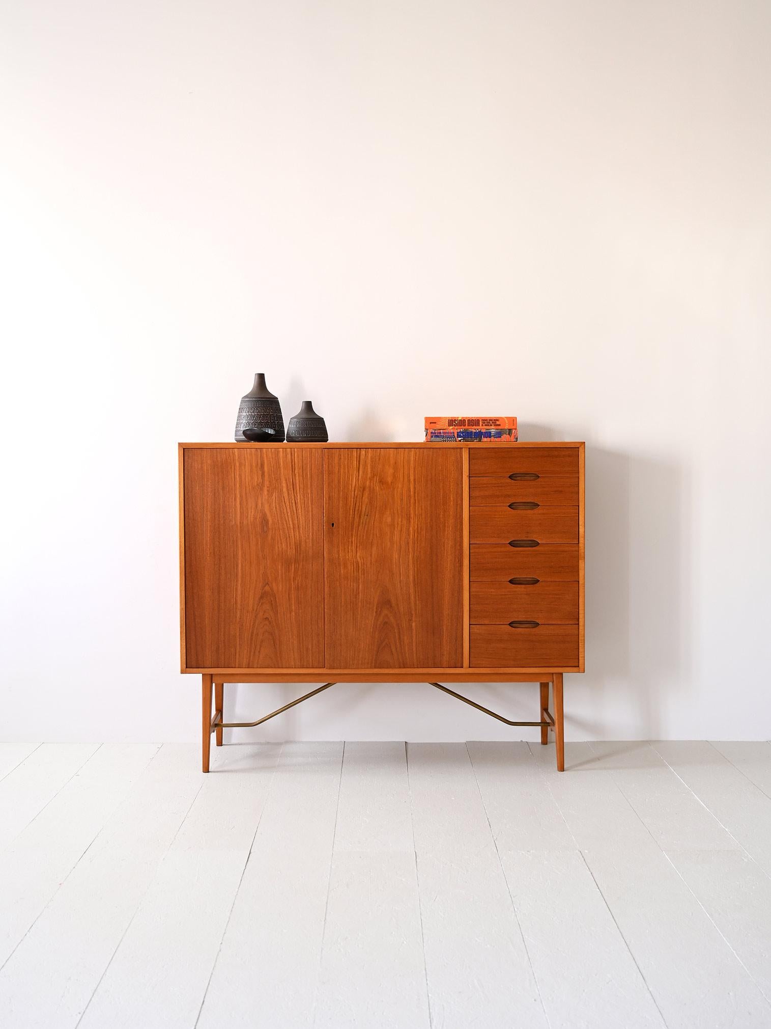 Simple, clean forms for this mid-century vintage Scandinavian teak wood sideboard/highboard.

Marked wood grain and classically Scandinavian shaped legs characterize this capacious sideboard.

The highlight is its height of 115 cm and shallow depth