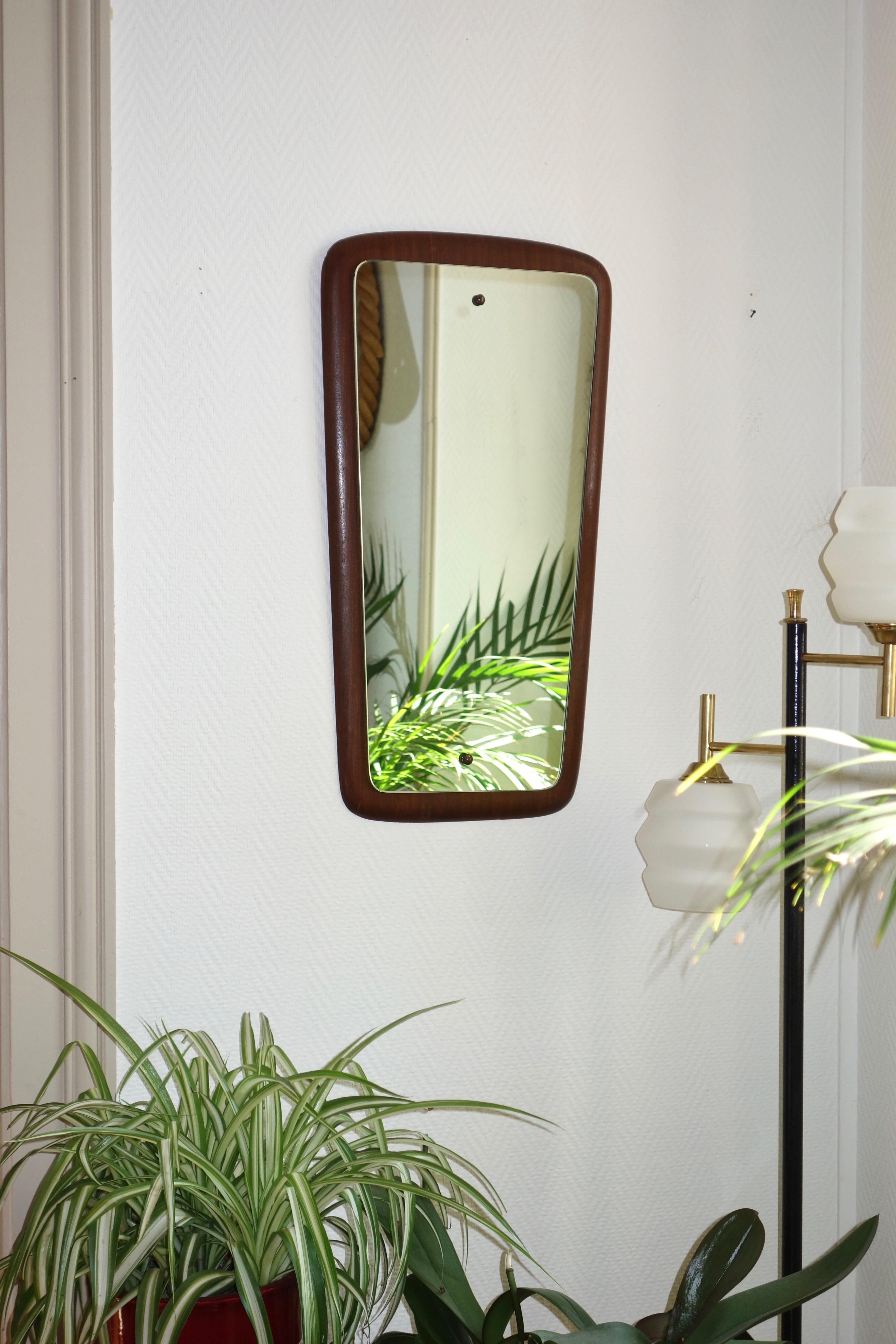 Scandinavian teak mirror from the 1960s. Sleek and clean lines, all in roundness. Fixings of the mirror on the teak support by 2 elements in aged brass. A beautiful decorative object, elegant and timeless. Wall hook by ring. Good state of