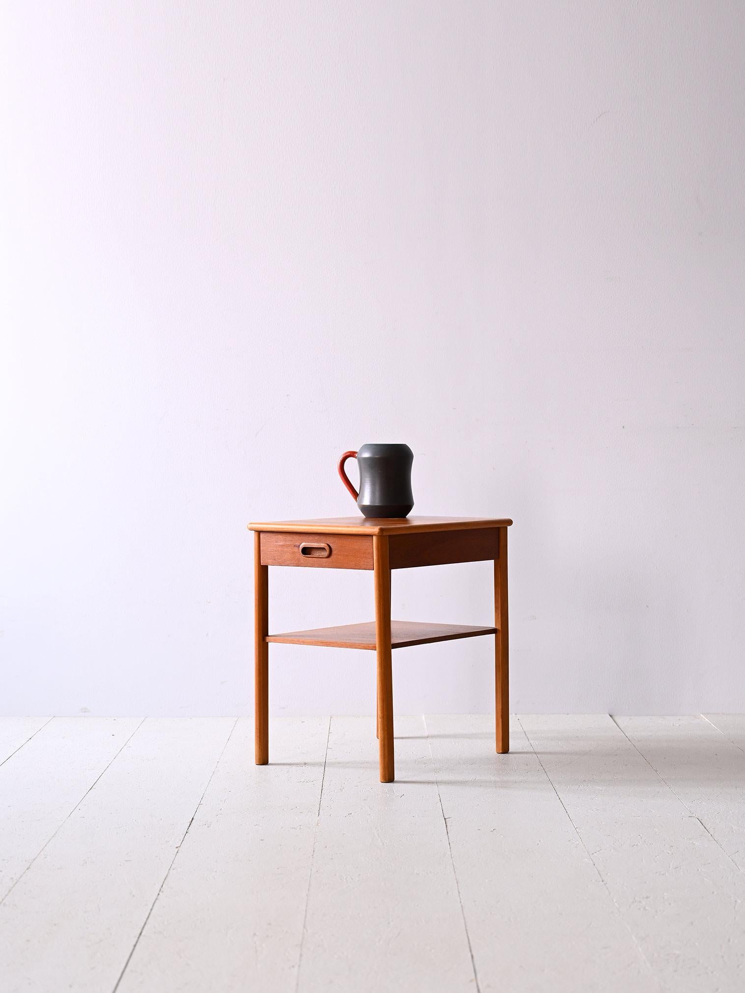 Originaler Nachttisch aus Teakholz aus den 1960er Jahren.

Ein Nachttisch im perfekten skandinavischen Stil, der die Vorliebe für einfache, moderne Linien nachzeichnet.
Bestehend aus langen, konisch zulaufenden Beinen, Zeitschriftenablage und