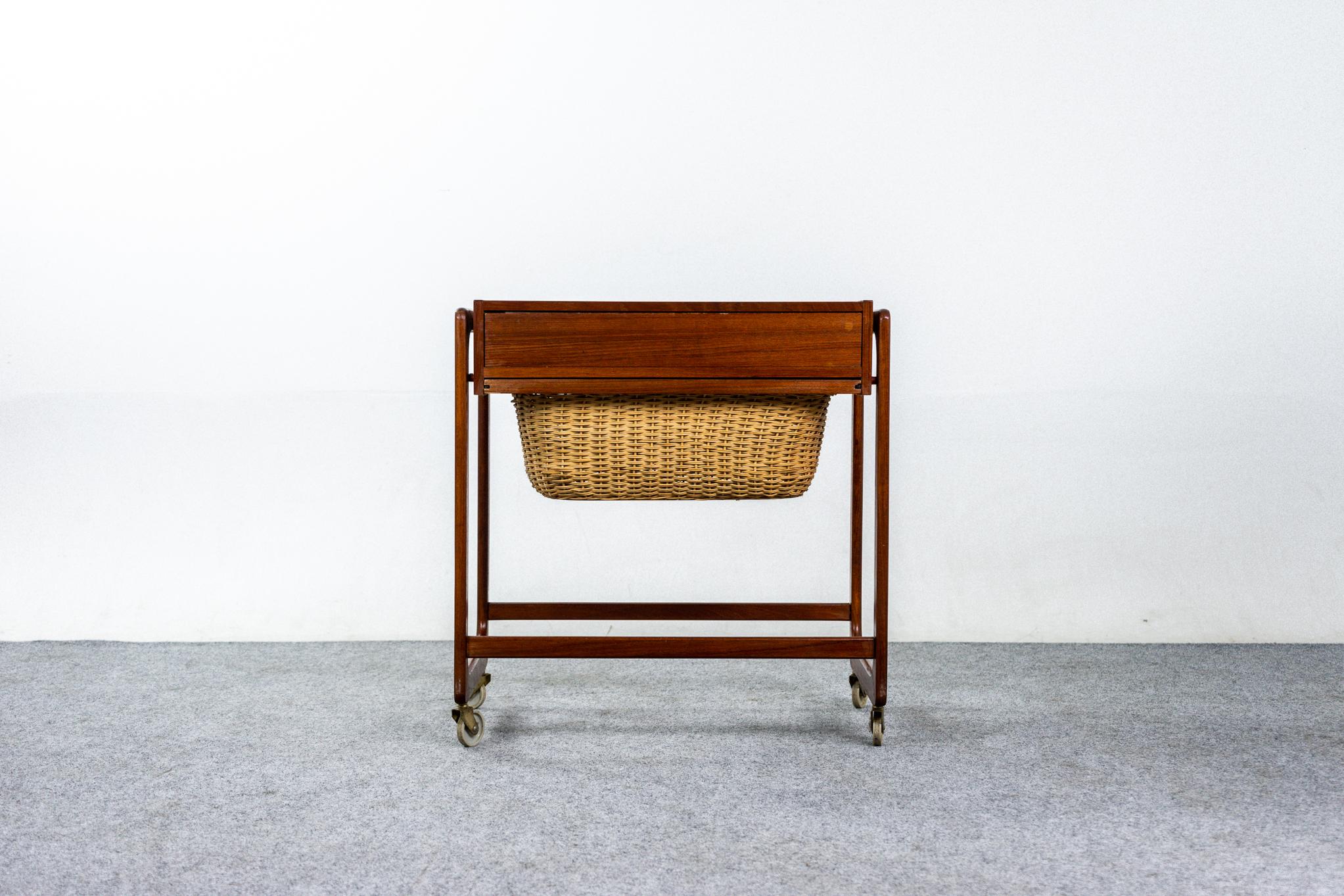 Teak Scandinavian sewing table with basket, circa 1960's. Delightful sewing table features original basket and fitted interior drawer, get organized! Original casters, smooth operating. Compact size works well as a side table or as a unique bedside