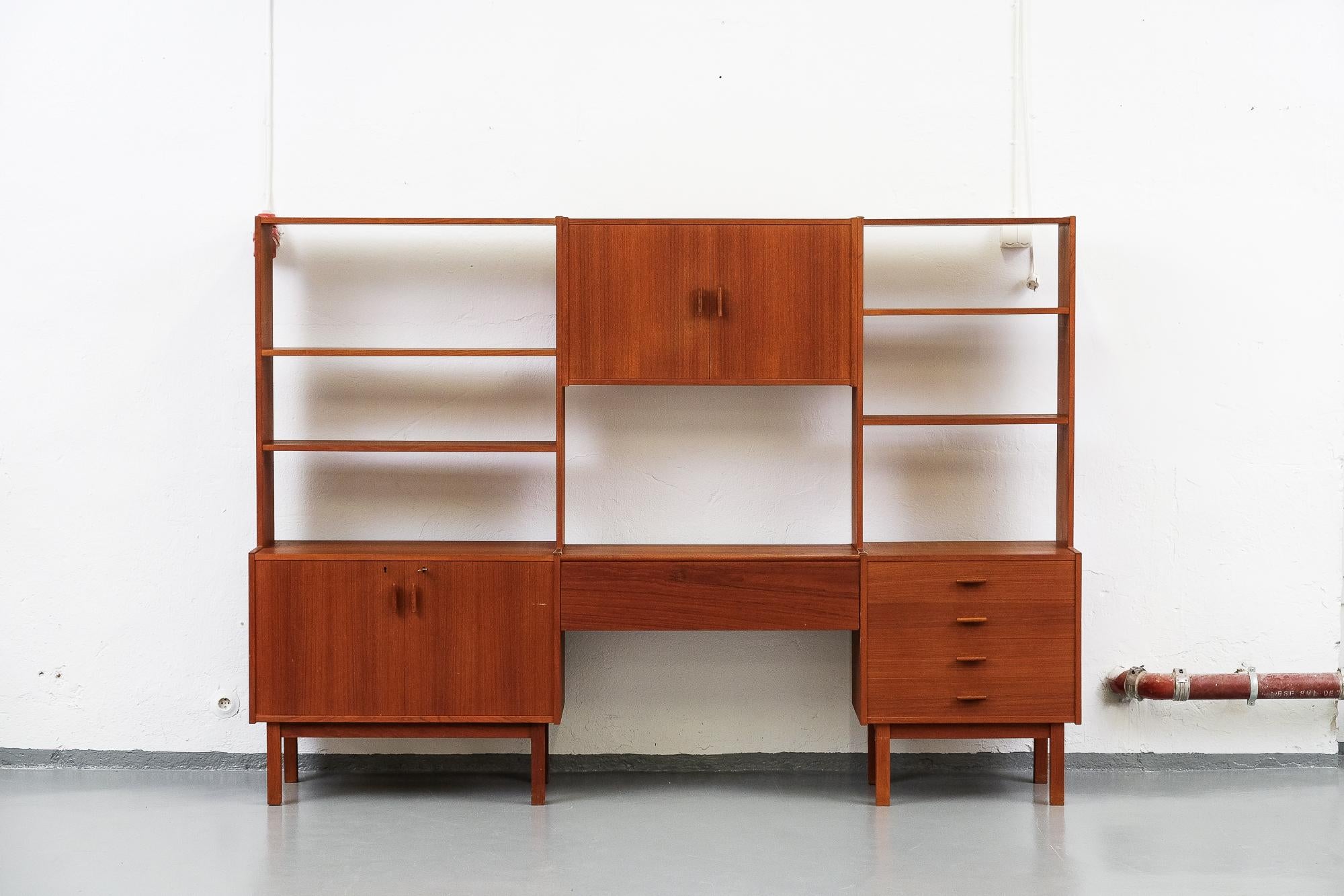 Beautiful 1960s Swedish teak shelving unit with adjustable shelves, one four-drawer chest, two cabinets and a extending work desk. Good original condition. Manufacturers stamp inside the cabinet.