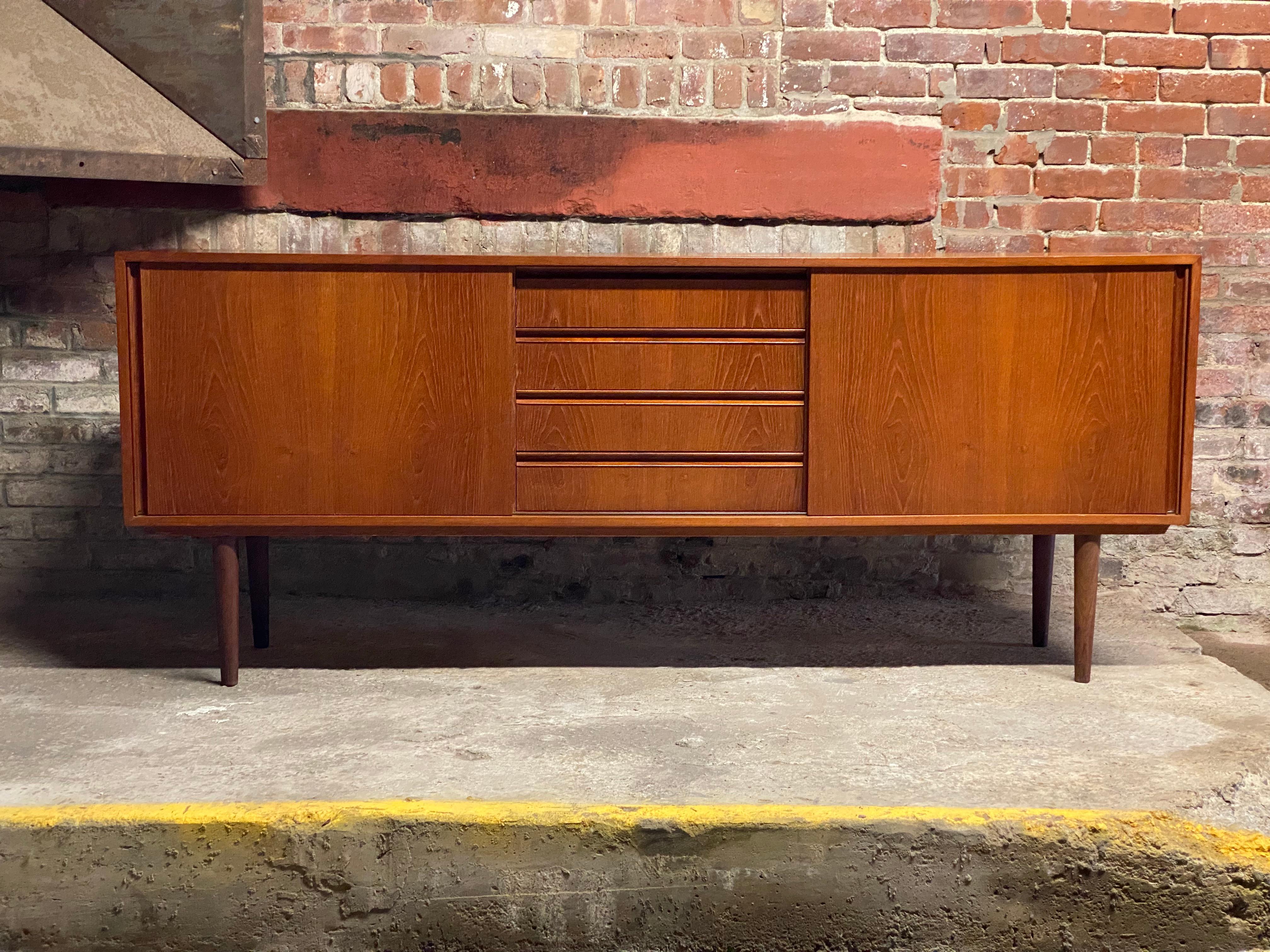 Sweet Scandinavian teak sideboard. Nicely figured teak veneer construction with two sliding door flanking four drawers. Four removable screw in legs. Maple interior with adjustable shelves. Nice and wide and not as deep as other Scandinavian