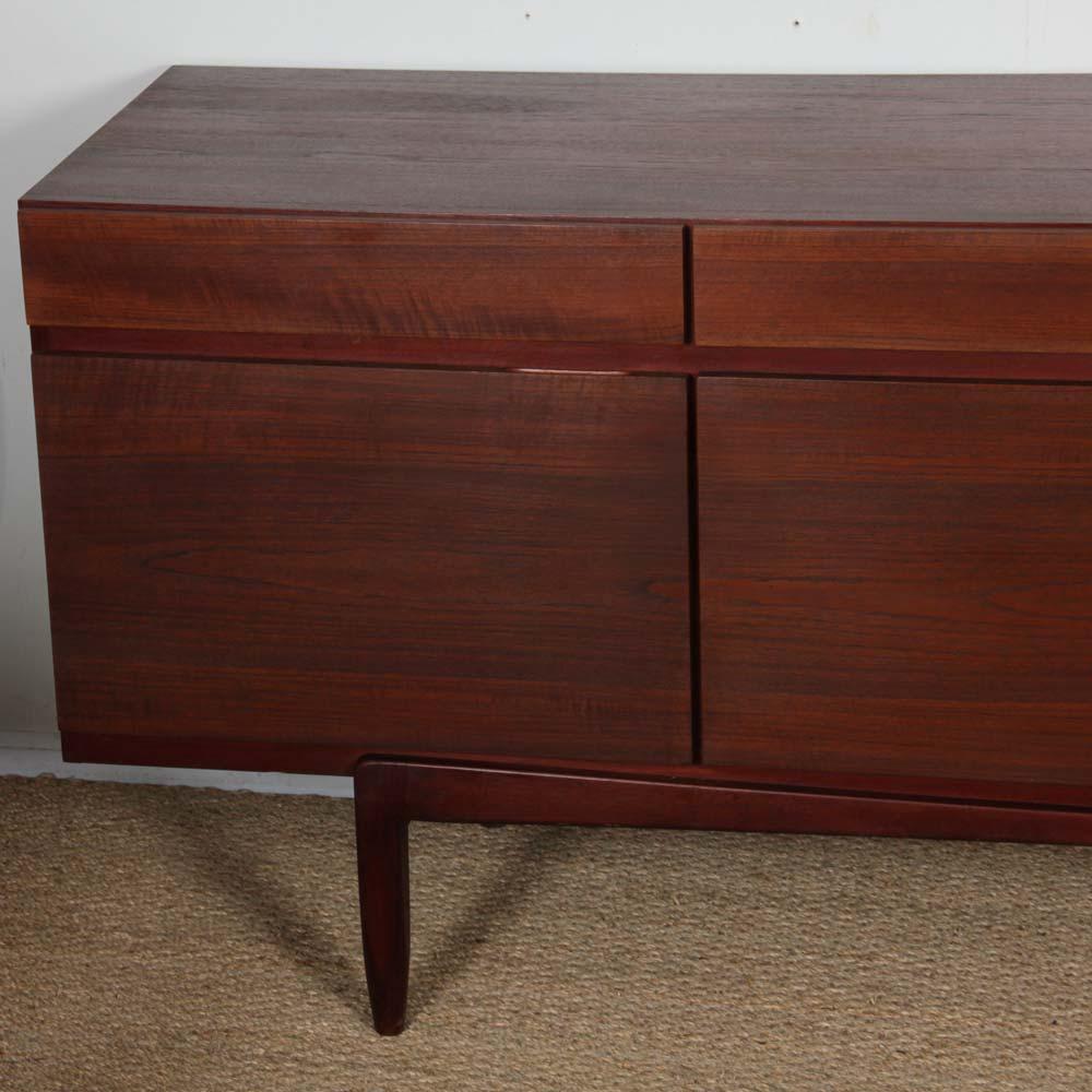 This Scandinavian teak enfilade was designed by the Danish designer Ib Kofod Larsen. It is the FA 66 model, published by Faarup Mobelfabrik in the 1960s. It opens with a series of 4 drawers and 4 doors. This large vintage storage unit is in good