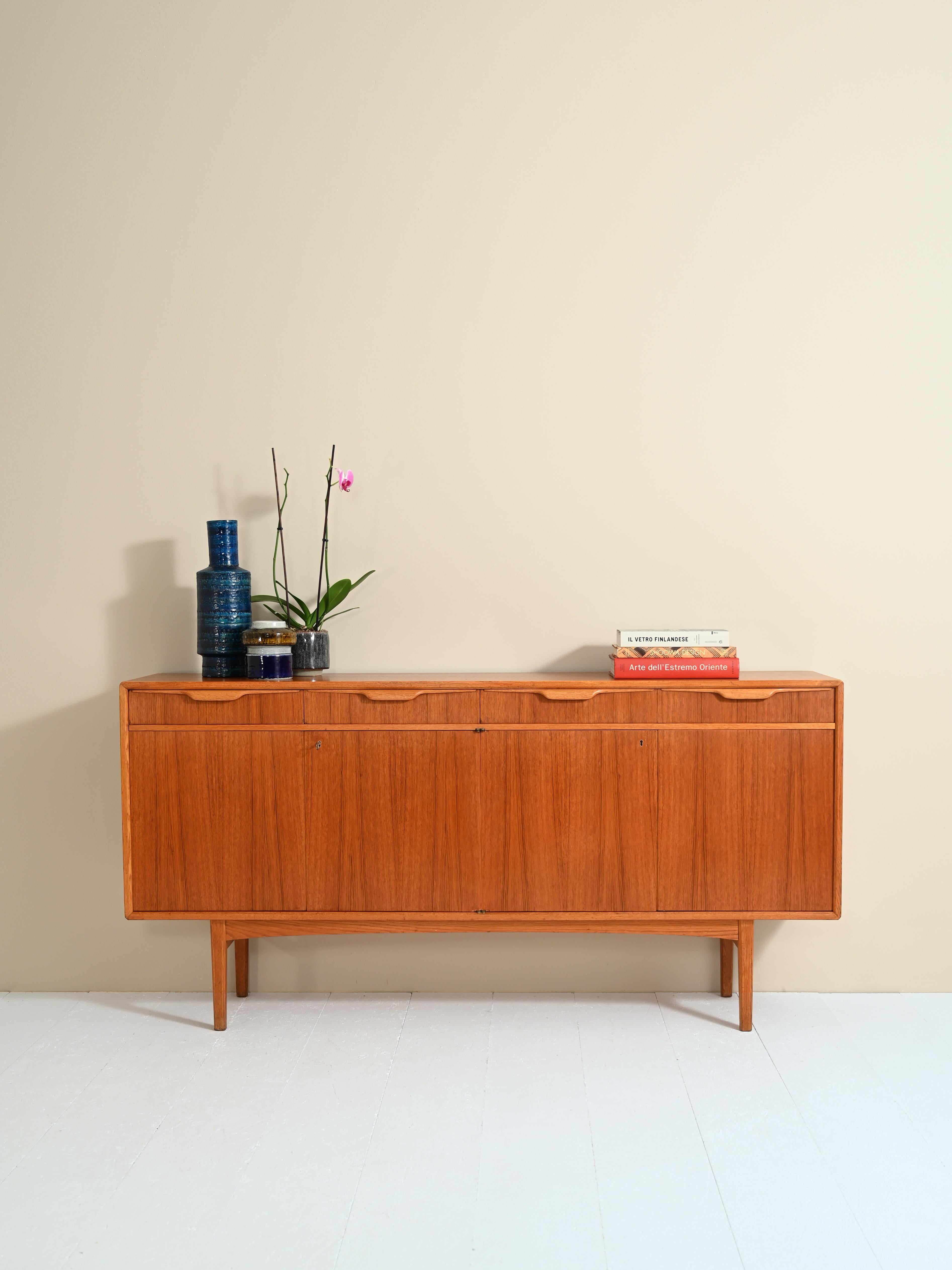 Original Swedish sideboard from the 1960s made of teak.
This classic and elegant piece features two large compartments with double hinged doors and 3 drawers with a curved wooden handle.
The square, minimalist legs are perfectly in keeping with