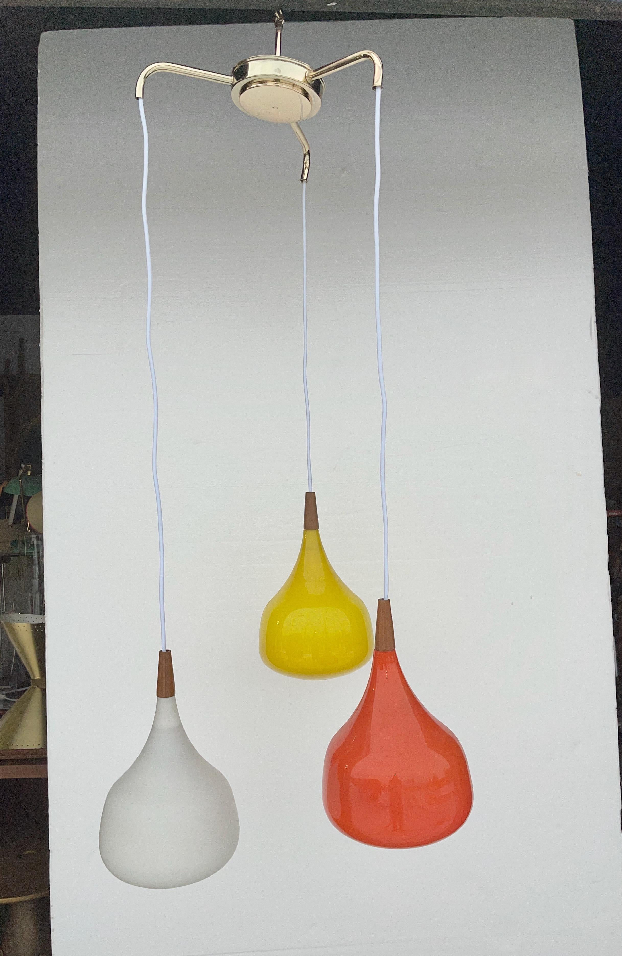 Vintage 1964 three globe pendant by Progress Lighting consisting of a brass plated flush mounted ceiling plate with three arms from which the white cord and colorful Swedish cased glass globes are suspended.
Cased glass globes are gloss yellow,