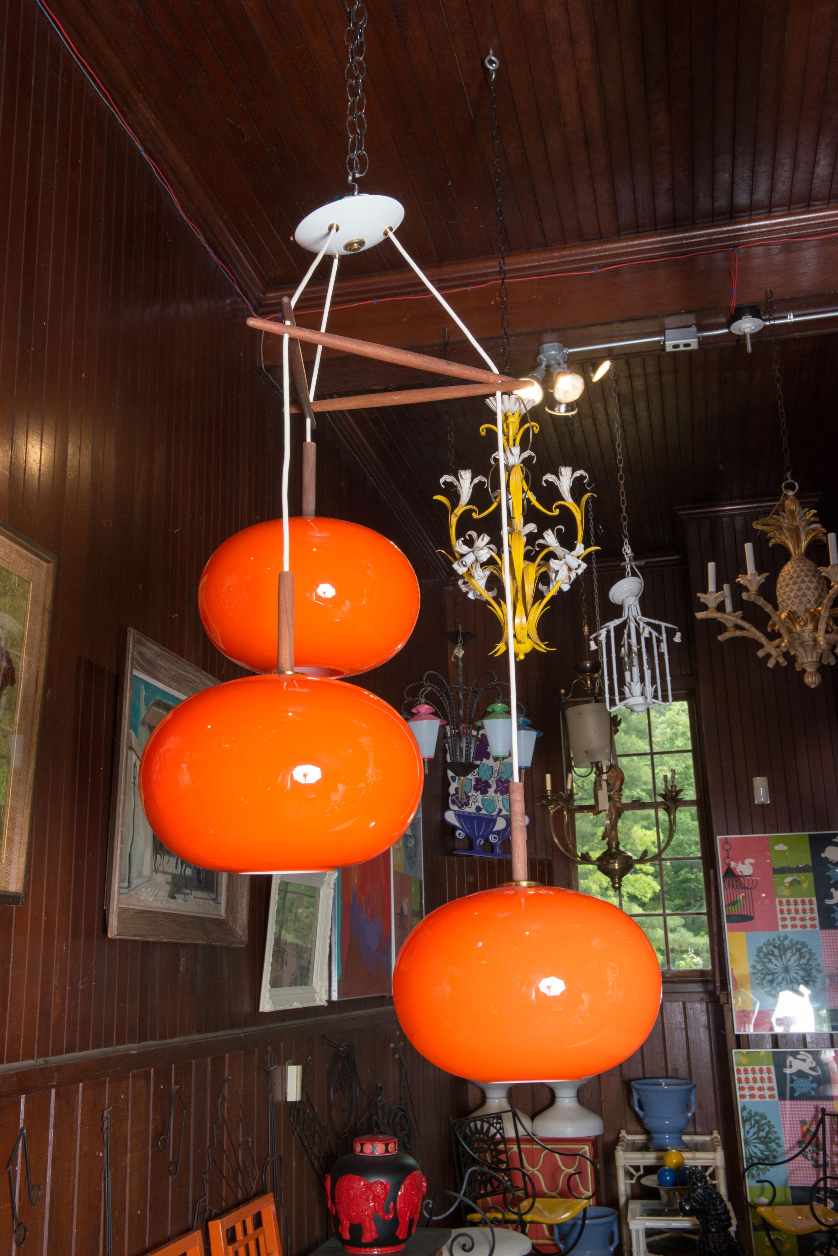 Lustre scandinave à trois globes en verre orange et blanc. La hauteur totale est de 47 pouces. La hauteur peut être ajustée selon vos besoins. Deux lustres sont disponibles. Chaque globe mesure 12