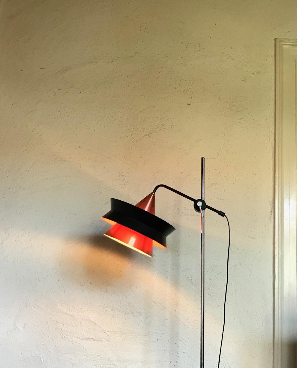 A fully adjustable tall floor lamp composed of a chromed steel stem, a black tiered aluminium shade with orange and rose copper alloy surfaces. This light called the 'Trava' was designed by Carl Thore's alias Sigurd Lindkvist. It was manufactured by