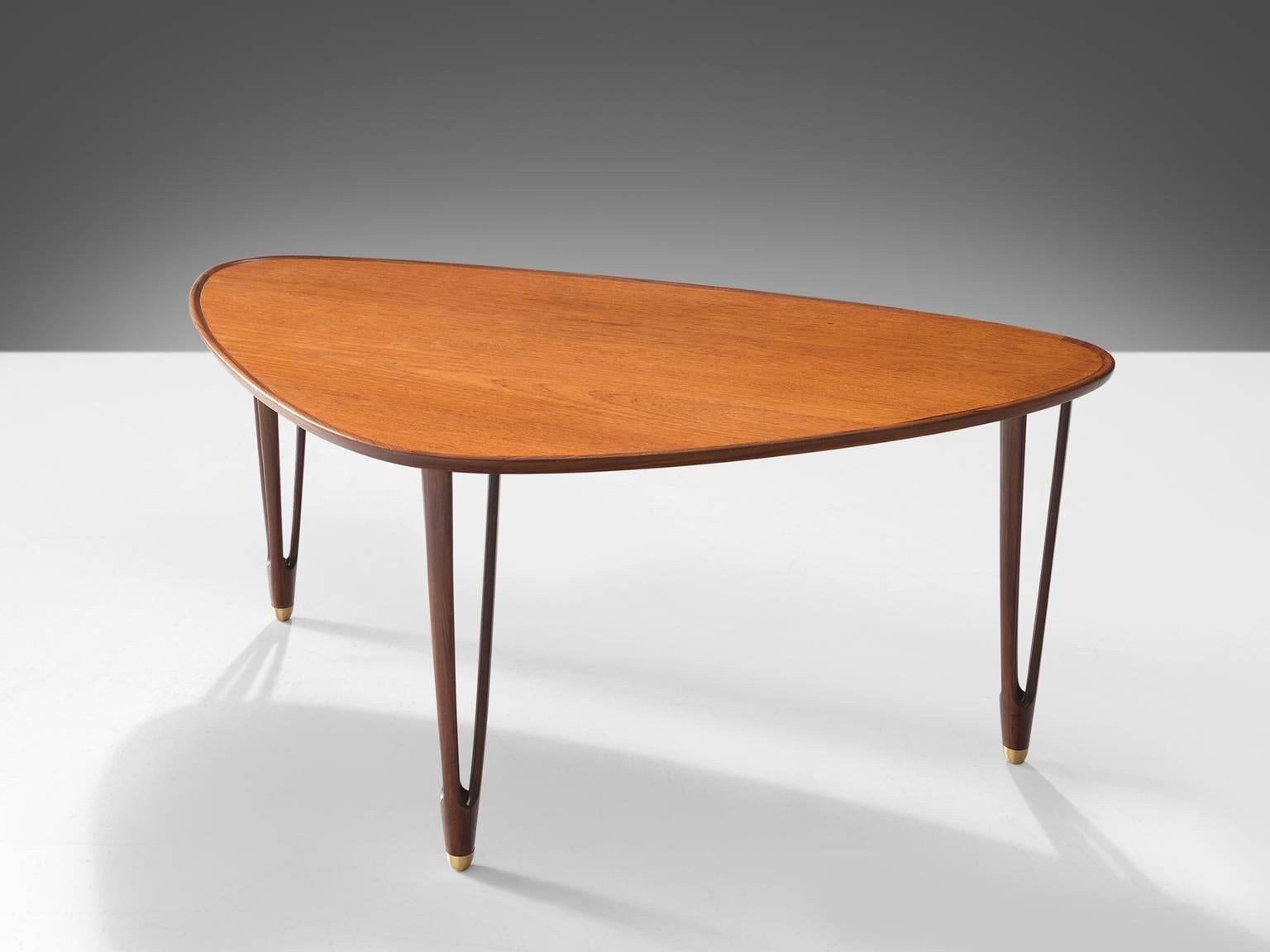 Coffee table, teak, brass, Denmark, 1950s. 

This graceful asymmetrical tripod coffee table made from teak with rounded edges and brass feet is produced in the 1950s. The side table is exemplary for Scandinavian mid-modern design. The quality of