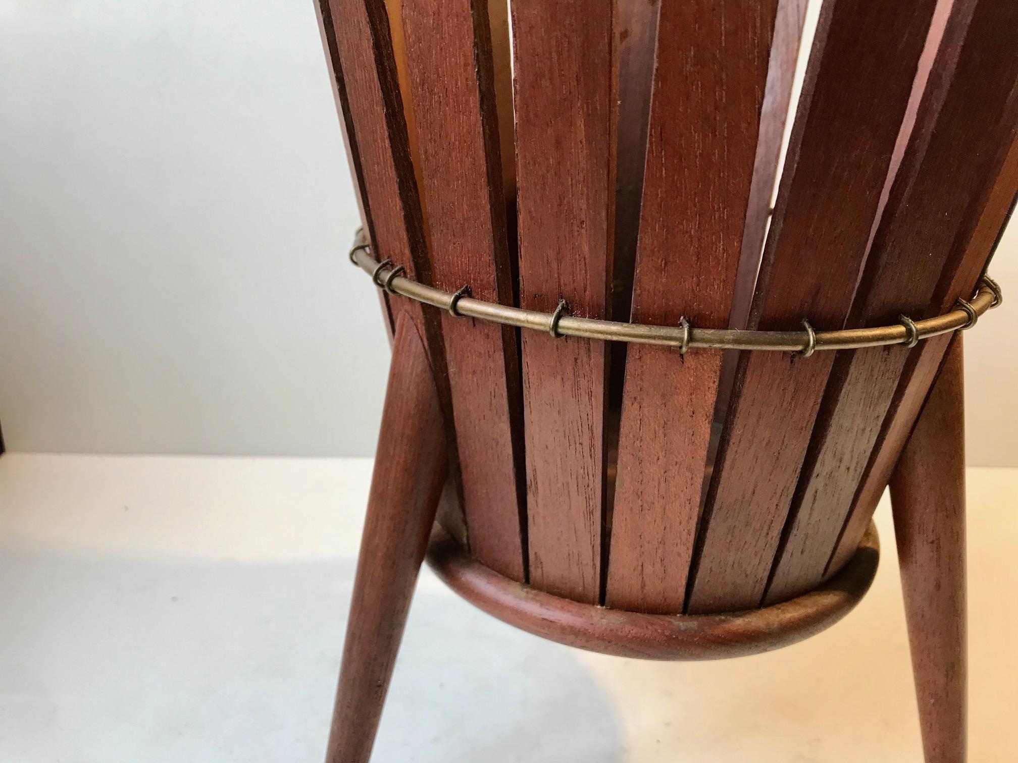 A Sputnik styled paper waste basket in teak featuring brass accents and details. Made anonymously in Scandinavia during the 1950s or 60s. Alternatively it can be used as a planted for a large flower or small tree. Measurements: H: 27.5, D: 21 cm.