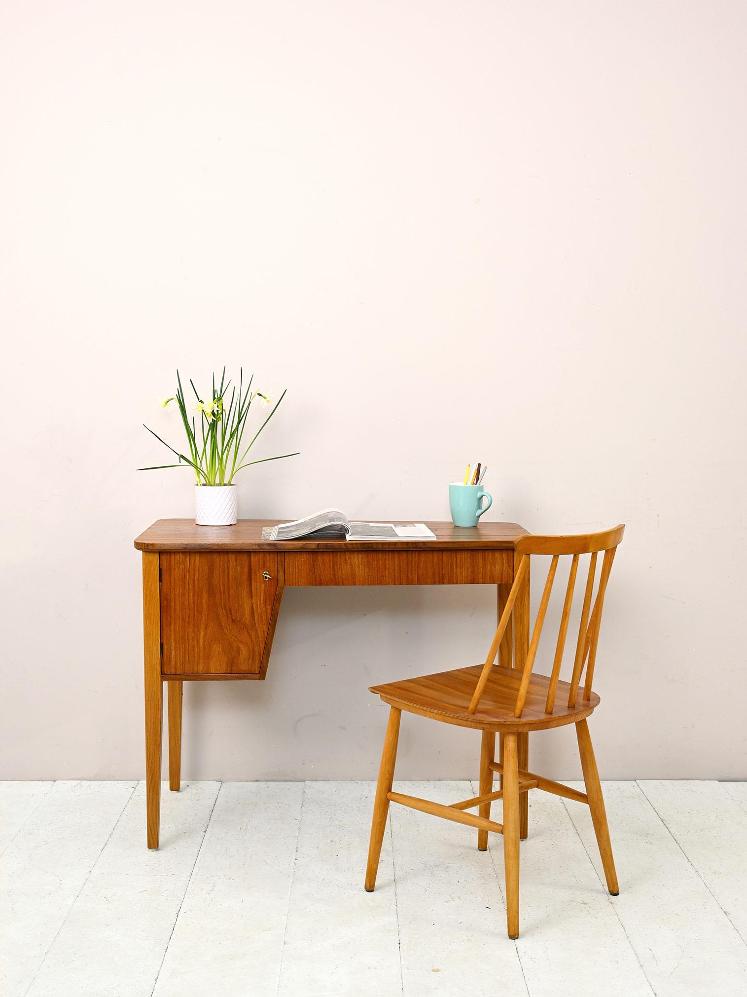 Small 1960s teak desk.

This small desk is perfect for recreating a work corner in the bedroom as well. 
It features long tapered legs in light oak wood and a teak frame that includes a drawer and a lockable storage compartment.
A retro-flavored