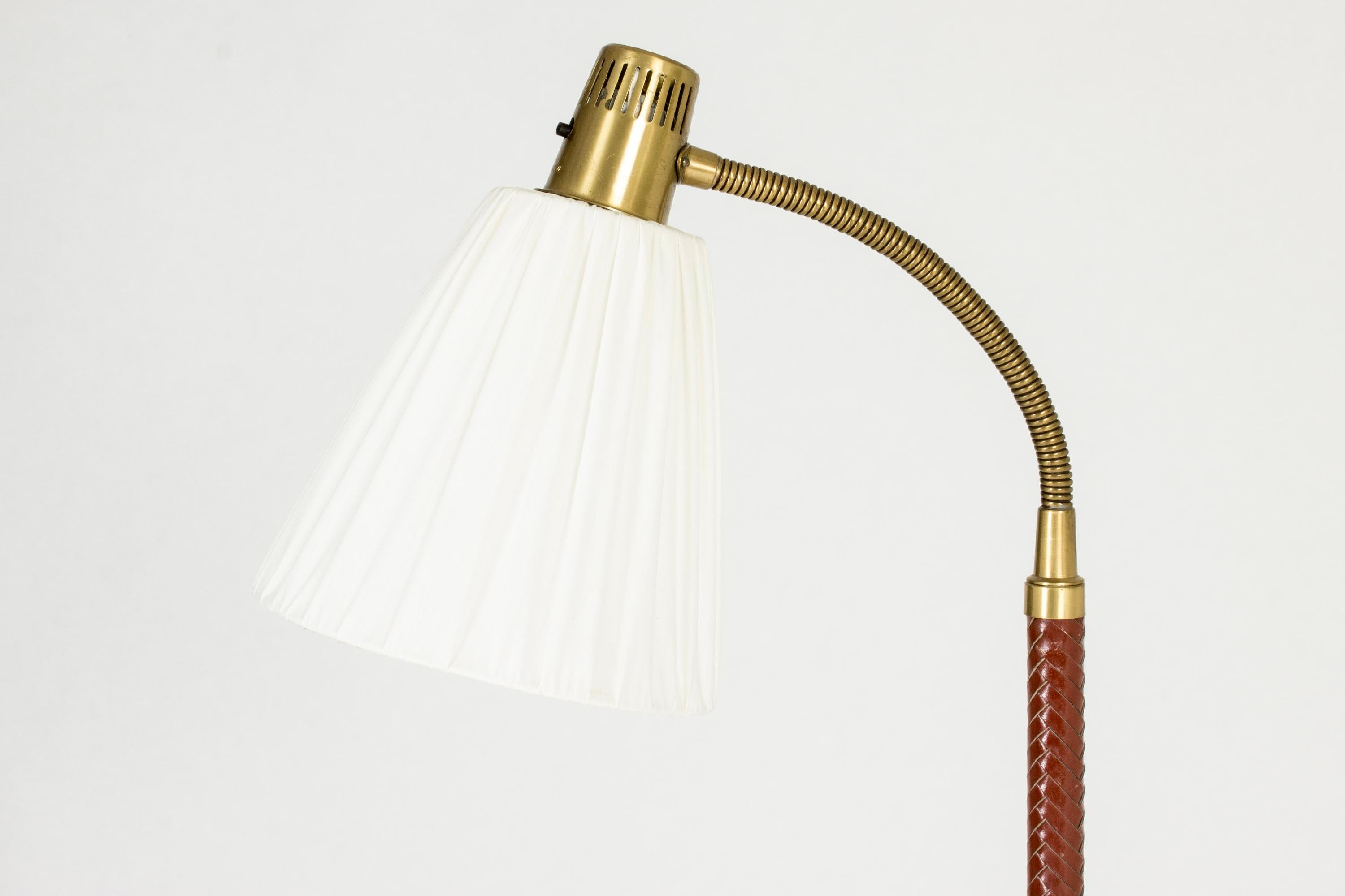 Elegant floor lamp by Hans Bergström, made from brass and dressed in wreathed red leather. Flexible neck.

About Hans Bergström: 
Hans Bergström was the owner and creative director of the lighting firm Ateljé Lyktan, which he founded in Åhus in the