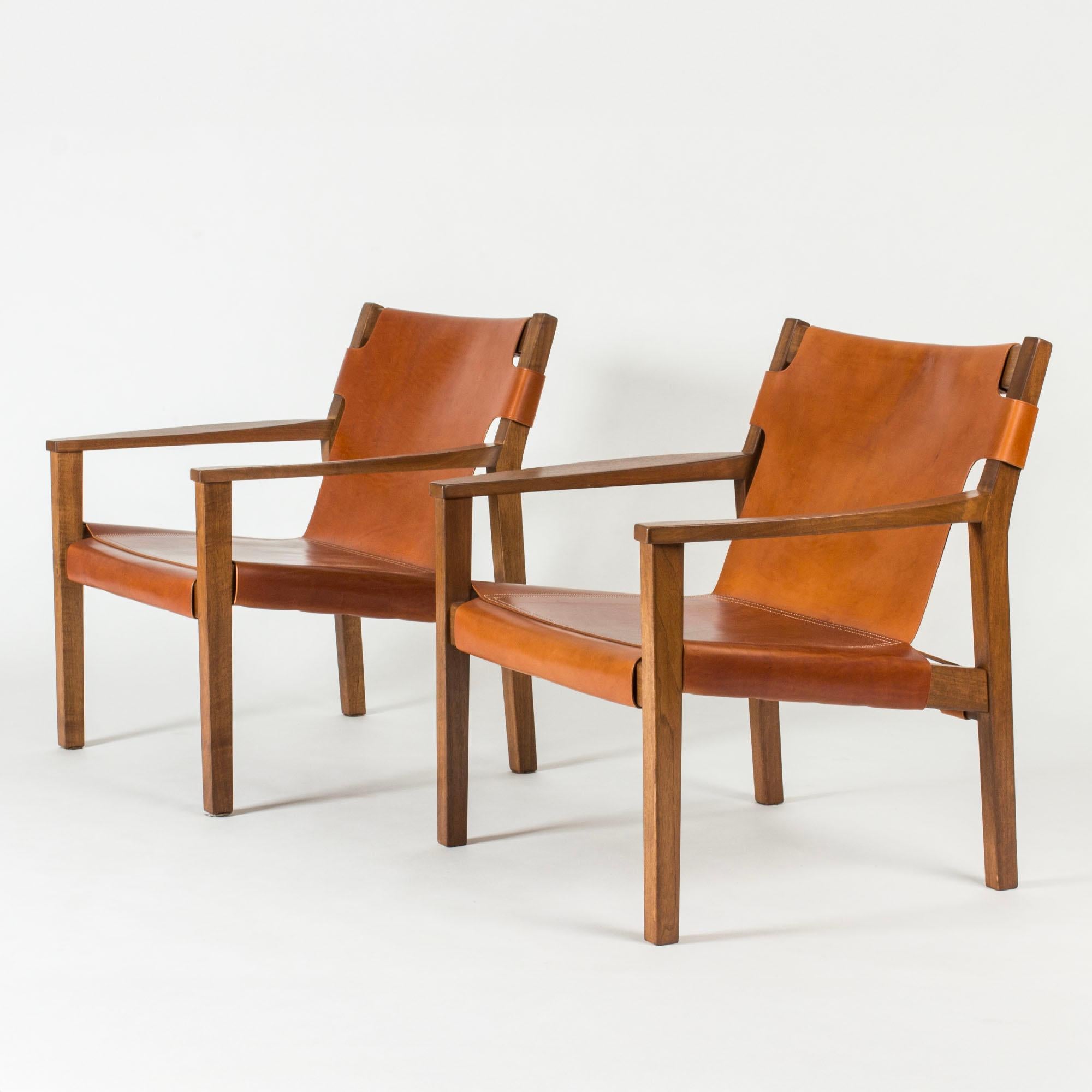 Pair of cool and elegant lounge chairs by Carl-Axel Acking, made from mahogany with leather seats and backs. Clean lines and subtle details, decorative white seams.