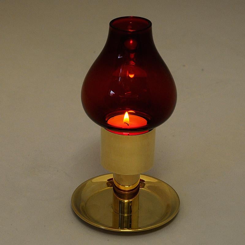 Rot gefärbter Glas-Kerzenhalter aus Messing aus den 1960er Jahren. Sockel aus poliertem Messing und tulpenförmiger Glasschirm. Verleiht beim Anzünden einen schönen Glanz. Abnehmbarer Schirm - kann also auch ohne den Glasschirm verwendet werden,