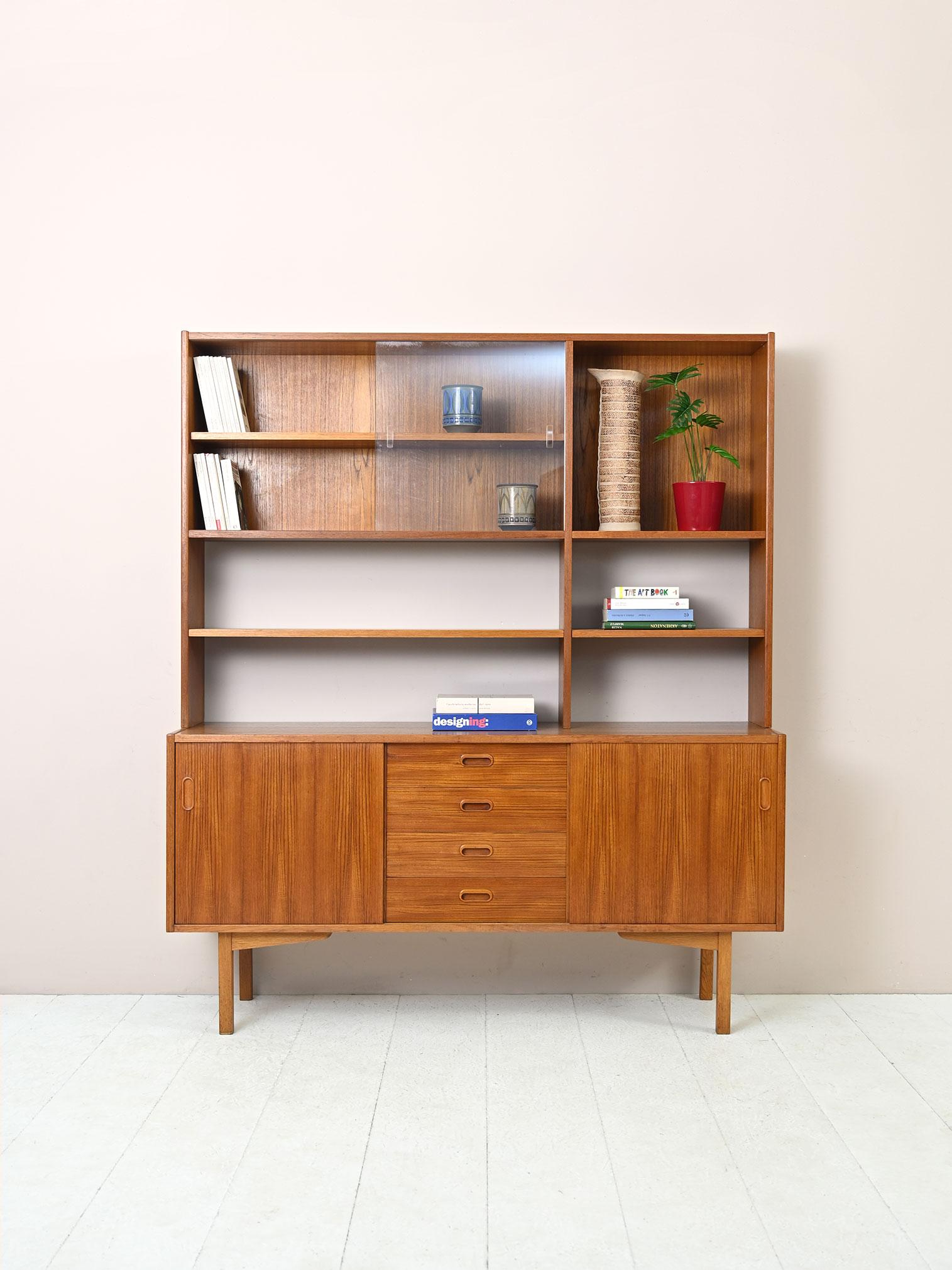 1960s teak cabinet with shelves and glass.

Original Swedish highboard consisting of two parts, the lower part is a storage cabinet with drawers and sliding doors, the upper part is a shelving system equipped with a glass cabinet.
The pronounced