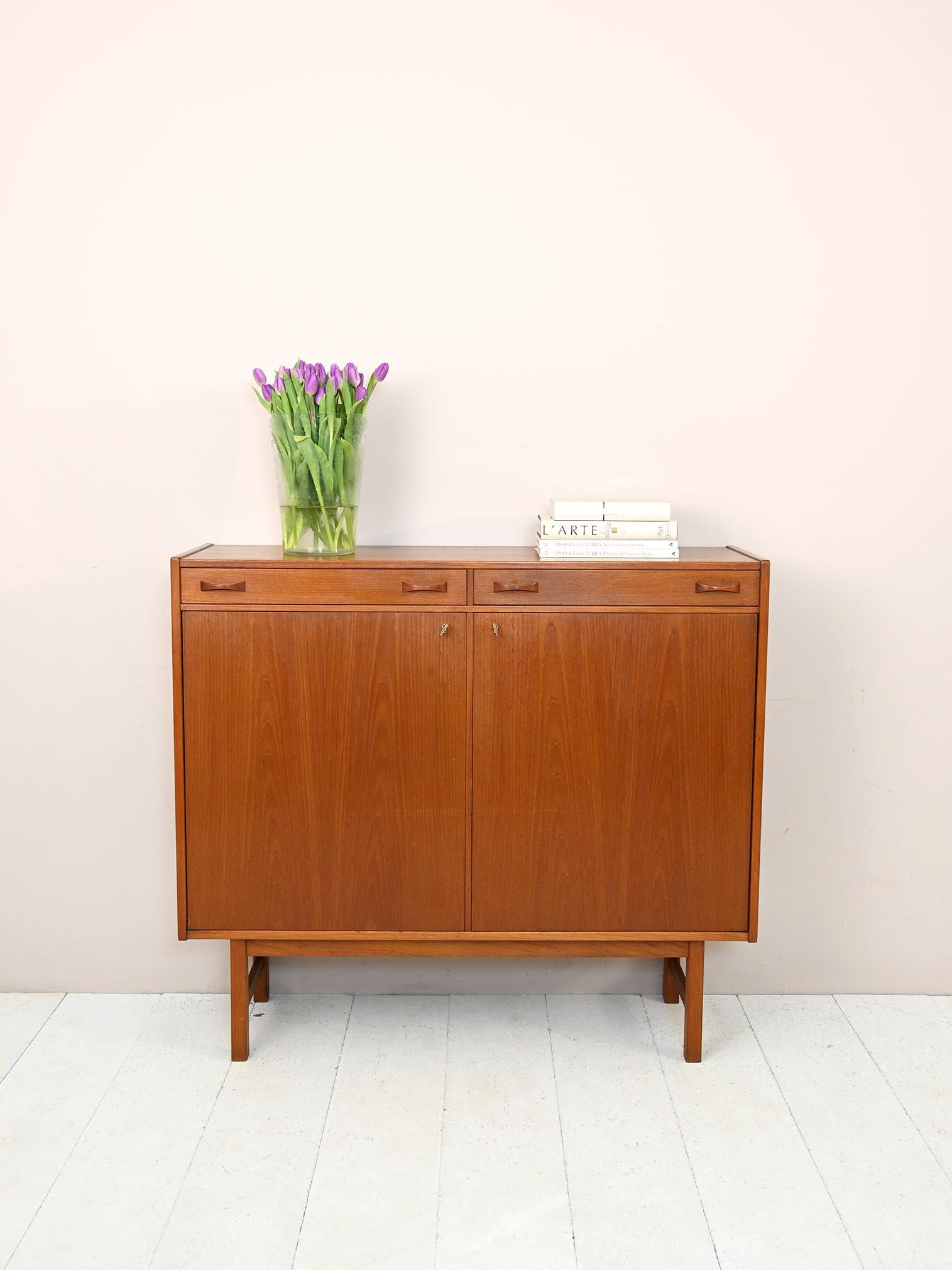 Scandinavian teak sideboard.

Swedish-made highboard from the 1960s, ideal as living room furniture.
The spacious storage compartment is divided into two compartments respectively equipped with a shelf. The compartment is closed by hinged doors