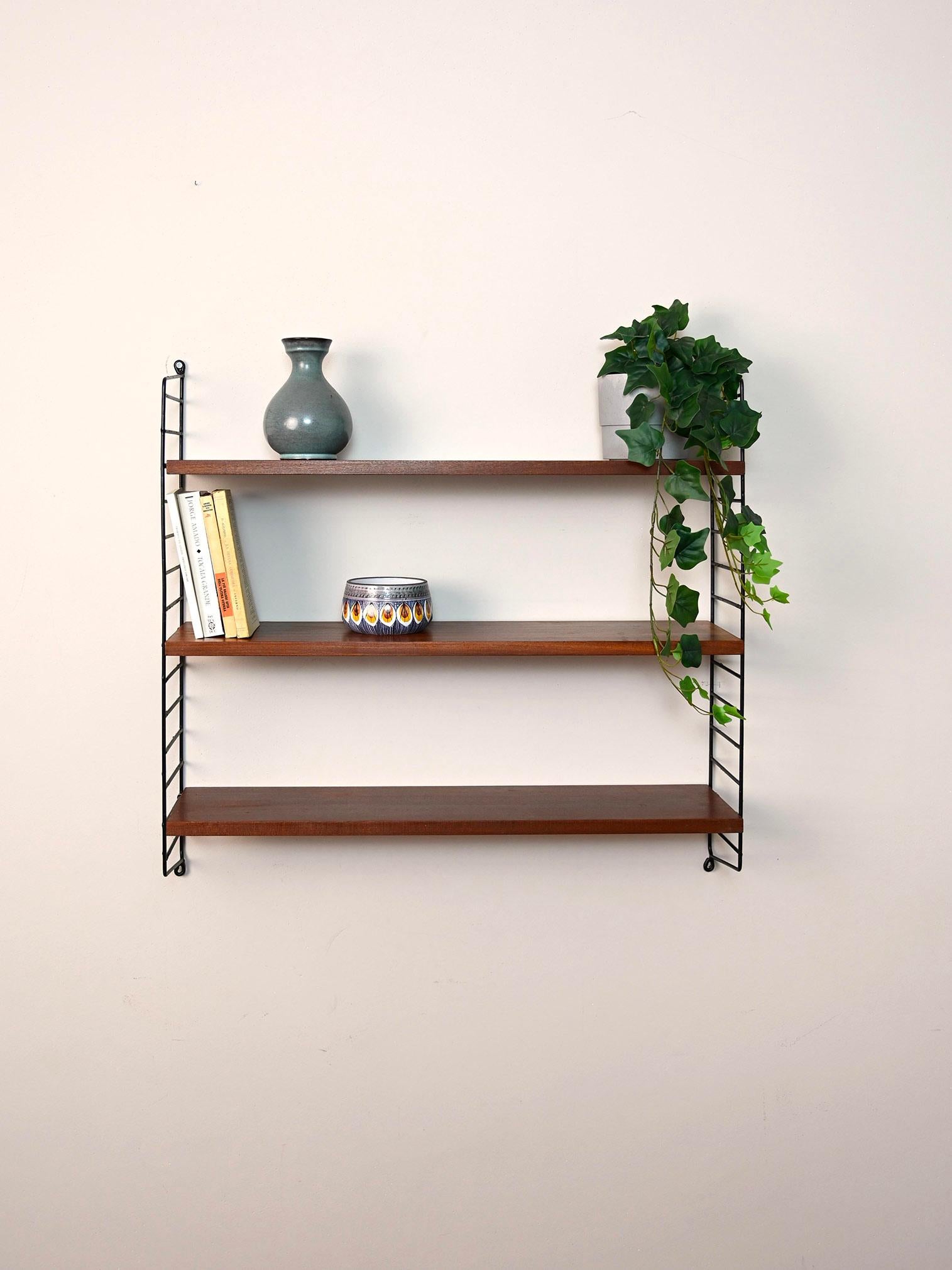 Original Scandinavian shelves from the 1960s.

This simple shelving system consists of a black metal side frame on which three mahogany shelves rest.
Simple and functional it can be hung in different rooms of the house.

Good condition. A