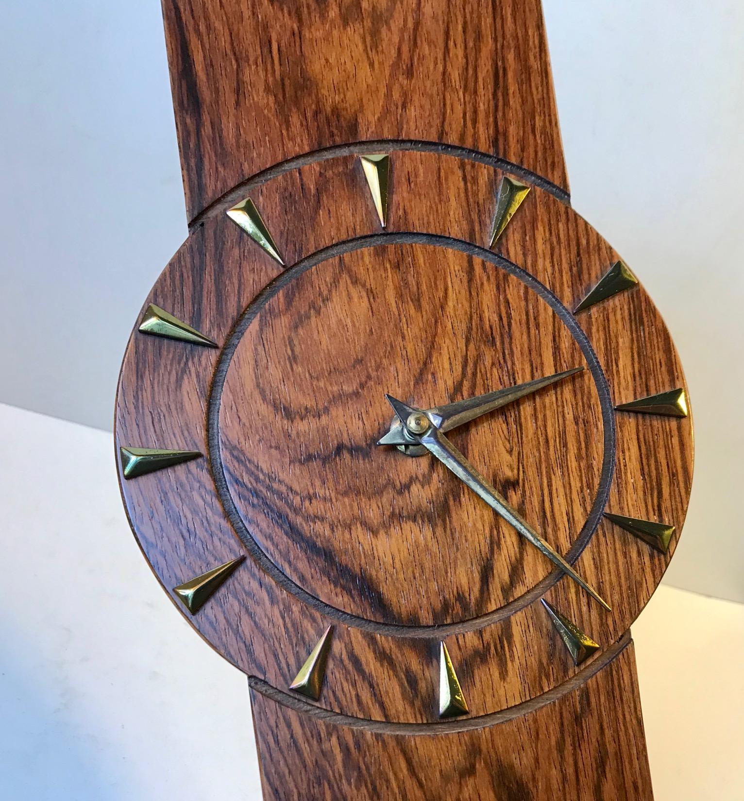 Coffin shaped wall clock with rosewood veneer to all visible surfaces. The dial is finished with hour markers and sword hands in brass. Anonymous Scandinavian watch makers circa 1960-1970 in a style reminiscent of Henning Koppel and Uno & Osten