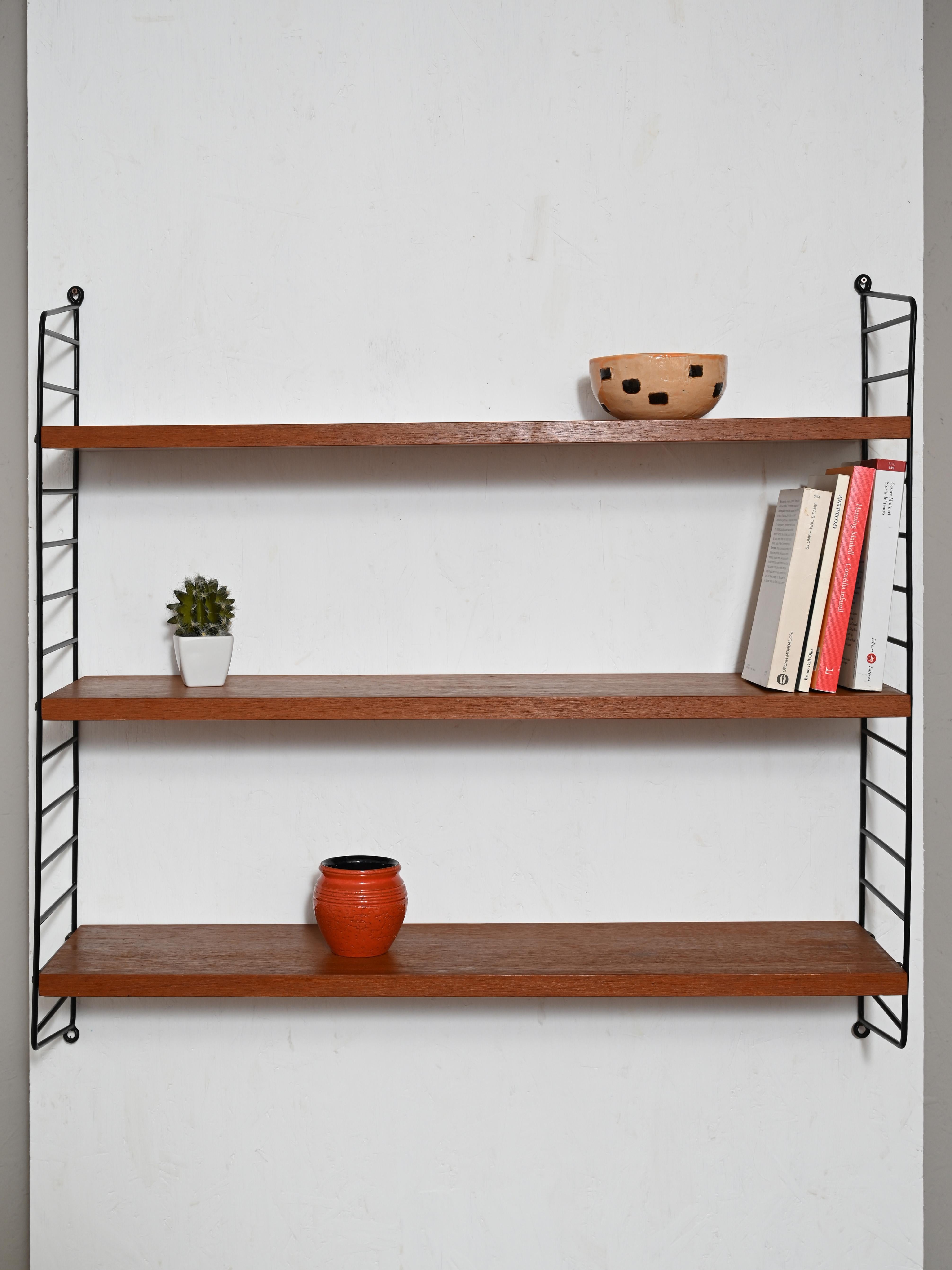 Wall shelving system with stamp of authenticity.
Composed of three teak wood shelving units with adjustable height and two side supports made of
black plastic-coated metal.
Use as a bookcase in the living room or as storage in the kitchen,
