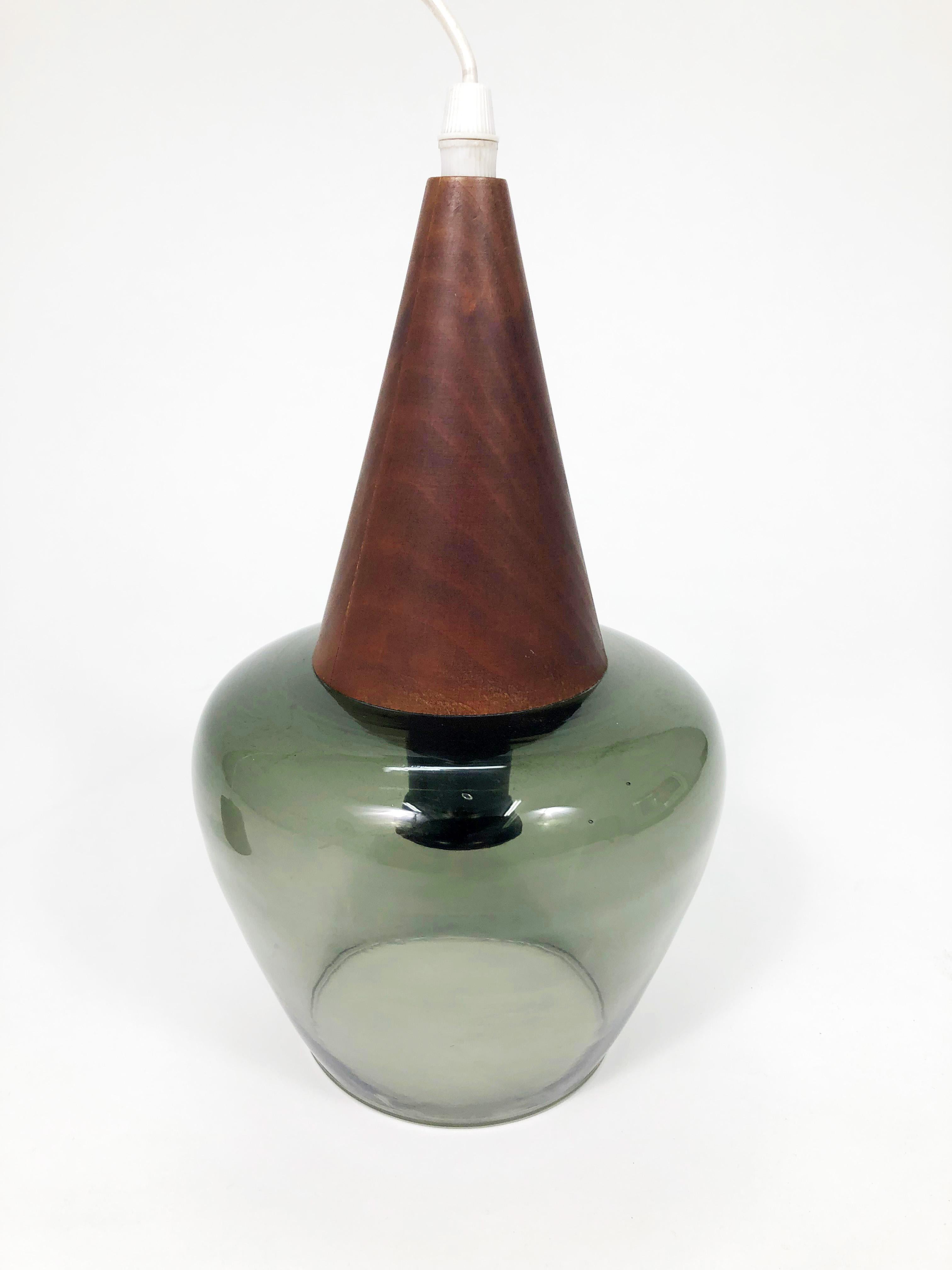 A handsome vintage mid-century Scandinavian hand-blown green glass pendant lamp.

Walnut veneer covers the metal cone hood above the glass shade.

Black cast-metal ceiling canopy with brass fitting included. Canopy dimensions: 2.86 in. D x 3 in.