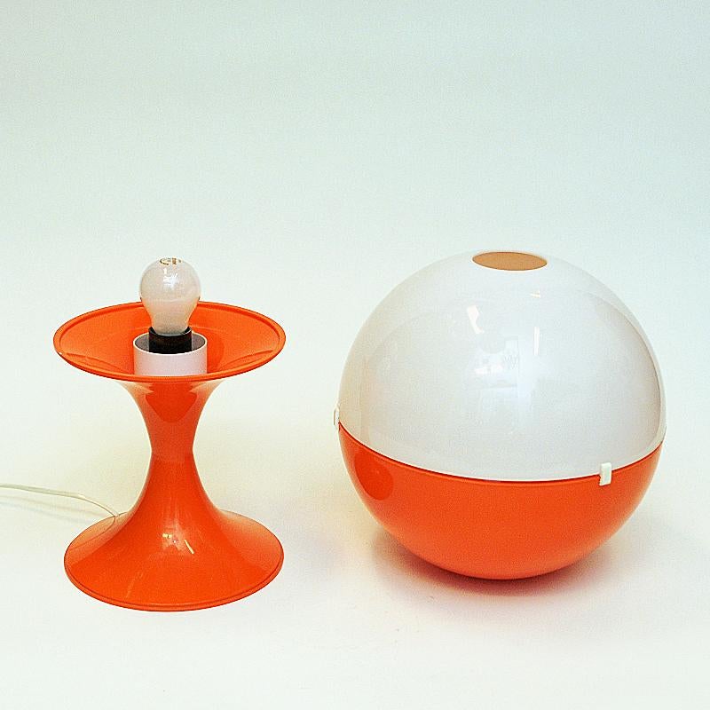 A special and rare Space Age tablelamp from the 1970s Scandinavia. The lamp globe consists of two removable acrylic parts. One orange and one white half circle - in which can be switched with each other to make to different lamps. Either the white