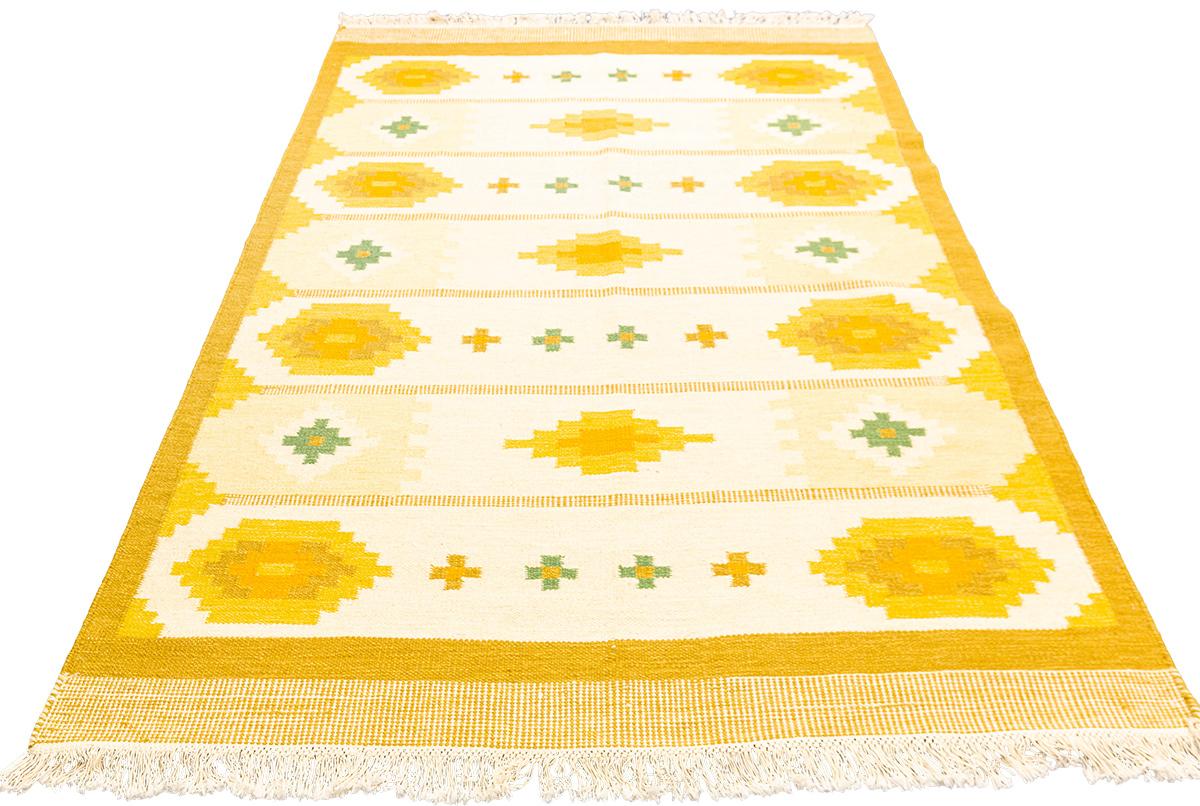 Présentation du tapis scandinave en laine  - le design suédois moderne avec une palette de couleurs chaudes et un subtil motif de croix. Avec son style à la fois audacieux et discret, ce design contemporain apportera un charme sans effort à