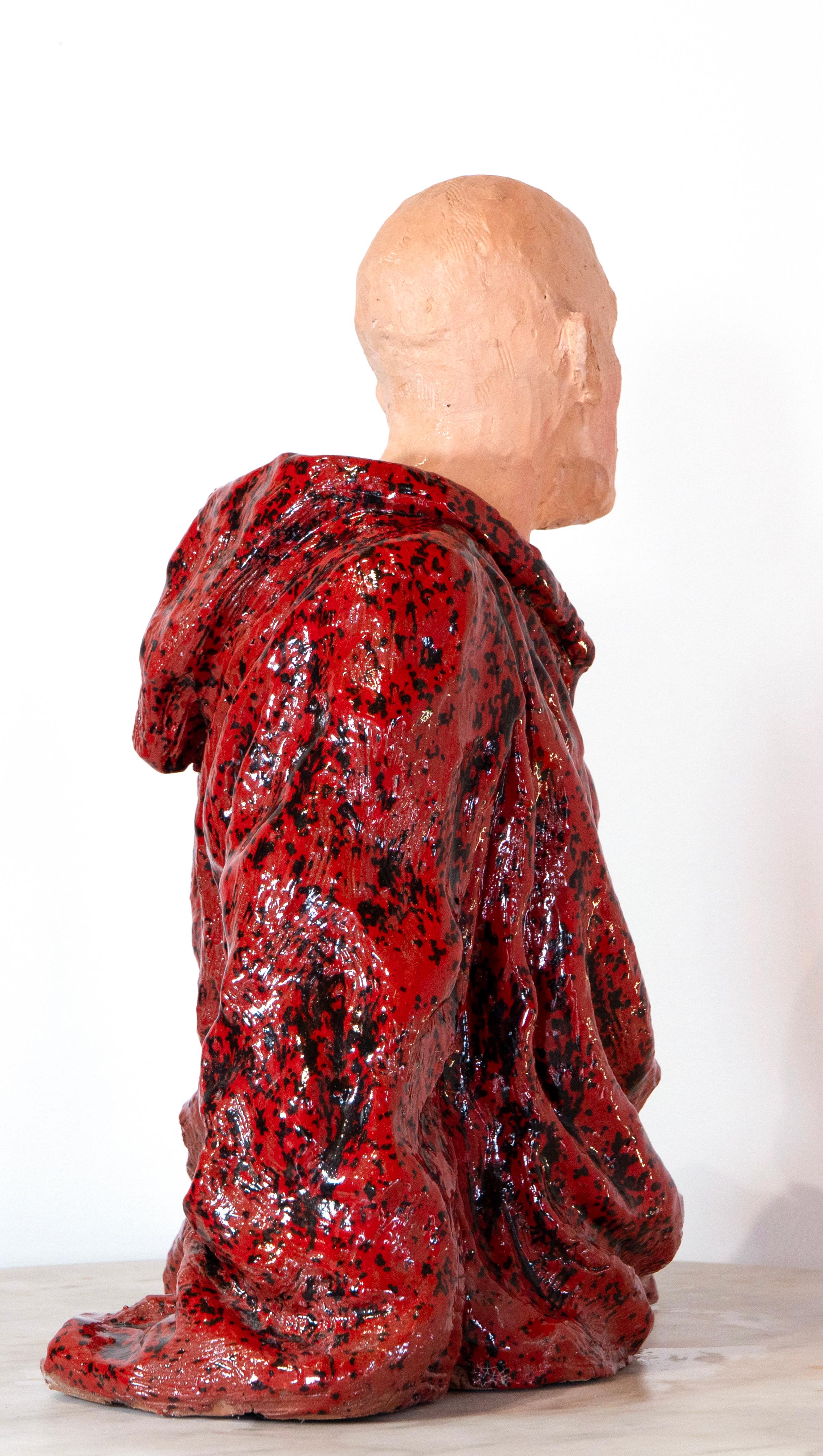 Bald head sculpture in vibrant red cloak blends glossy low-fire glaze and oil-painted detail to evoke emotional introspection. Bald Man in Red Cloak (48 × 42 × 22 cm) by Aldonza presents a hyperrealistic male visage—shaved scalp, closed eyes, and