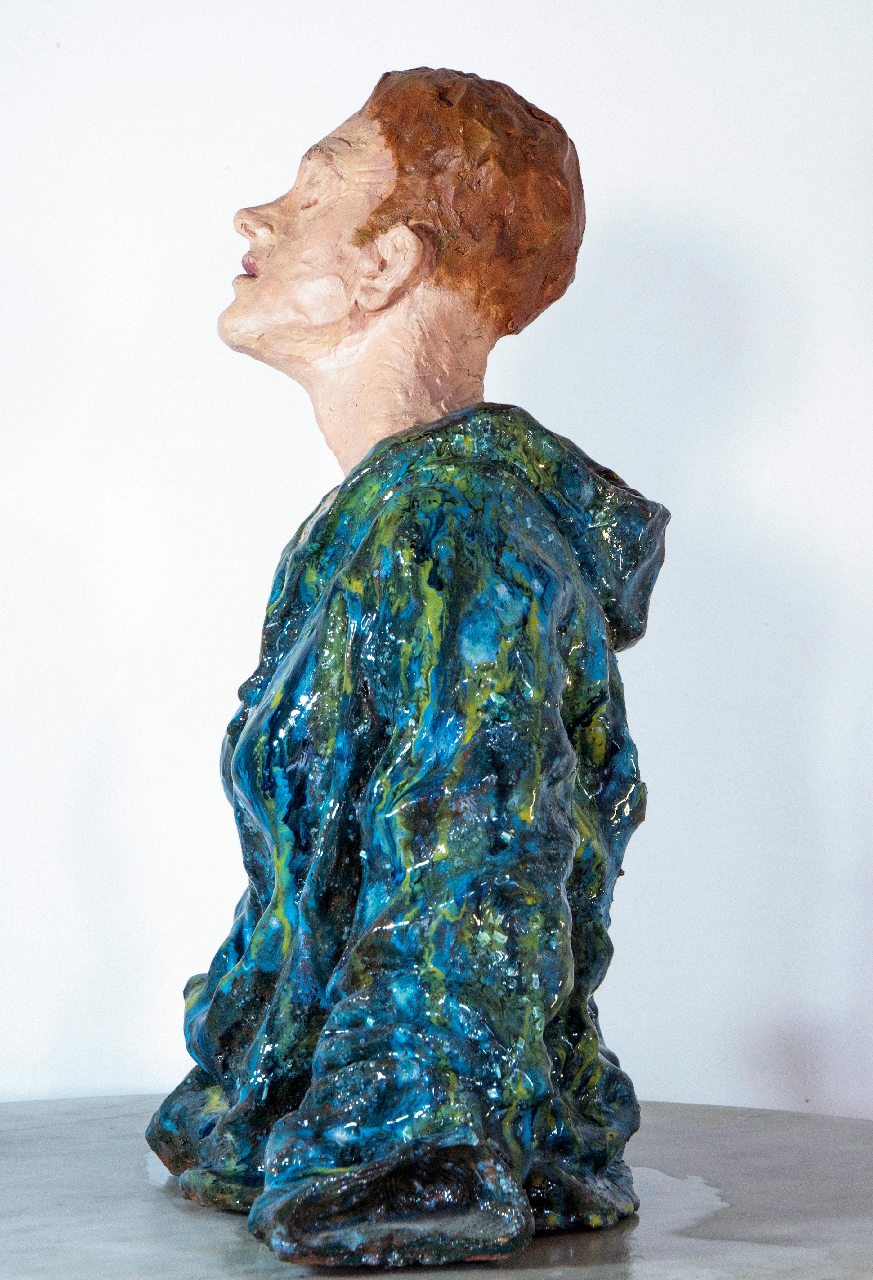 Low-fired glazed ceramic head sculpture features a radiant blue cloak and oil-painted facial details, exploring the tension between exposed identity and hidden emotional depths. Woman in Blue Cloak measures 48 × 42 × 22 cm and weighs 5 kg, crafted