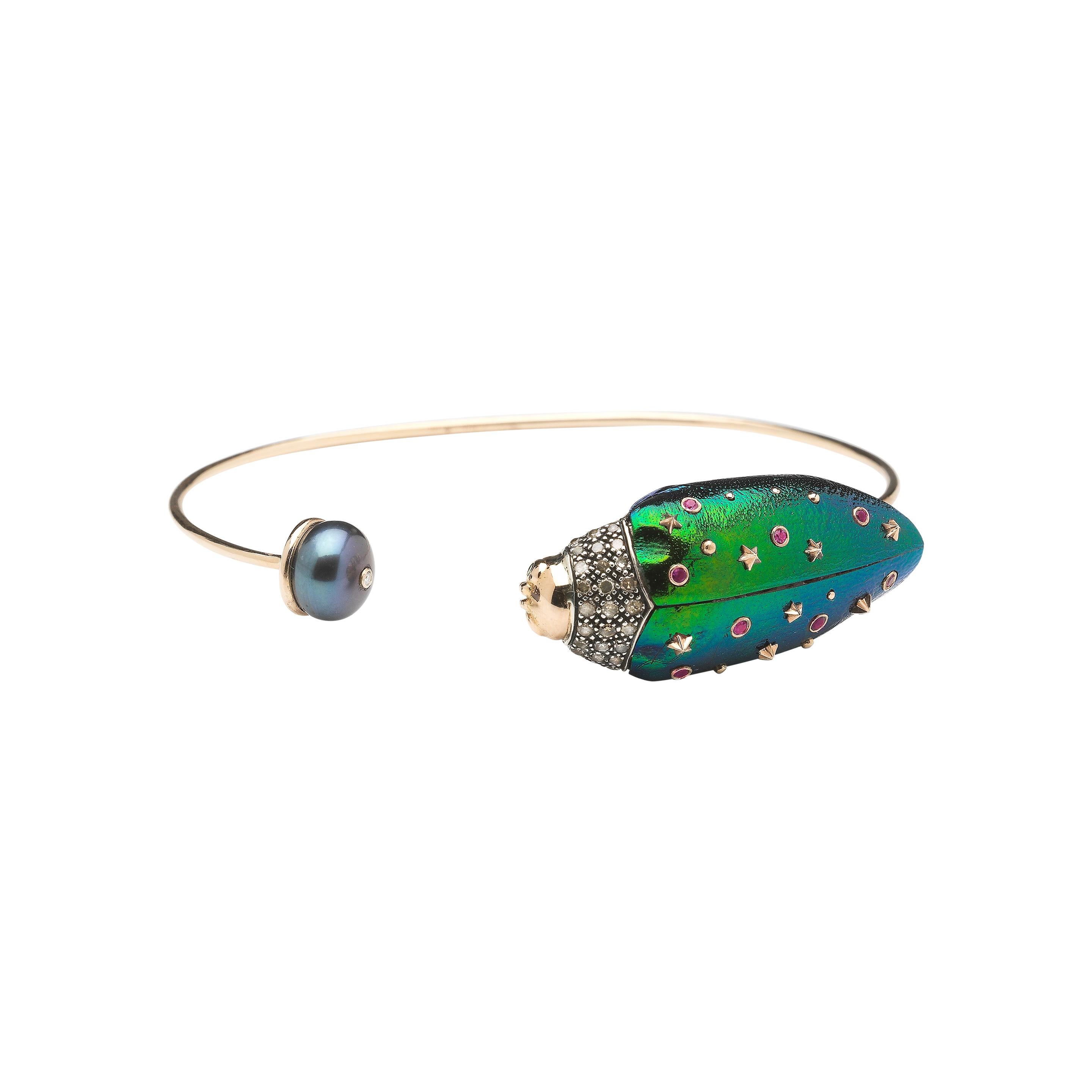 

Elegant and delicately-crafted, this bangle is fashioned in 18k rose gold as an open-ended design. On one end sits a scarab in 18k rose gold and sterling silver, set with real scarab wings embellished with amethyst and pink sapphires for an