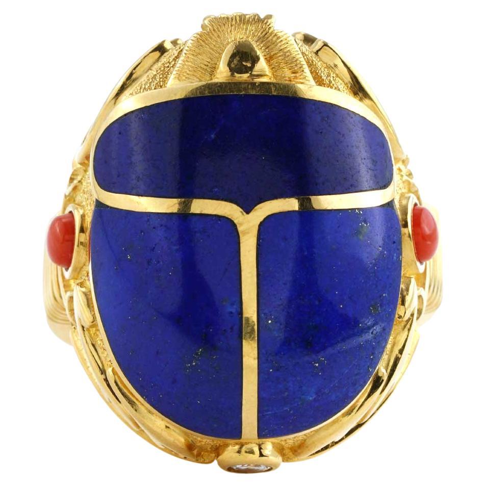 Previously-owned Scarab Lapis Lazuli Ring. The ring is made of 18K yellow gold and weighs 21.30 DWT (approx. 33.13 grams). Centering this stunning ring are 3 Lapis Lazuli gems. It also has two round G-color, SI-clarity diamonds weighing 0.20 CTTW