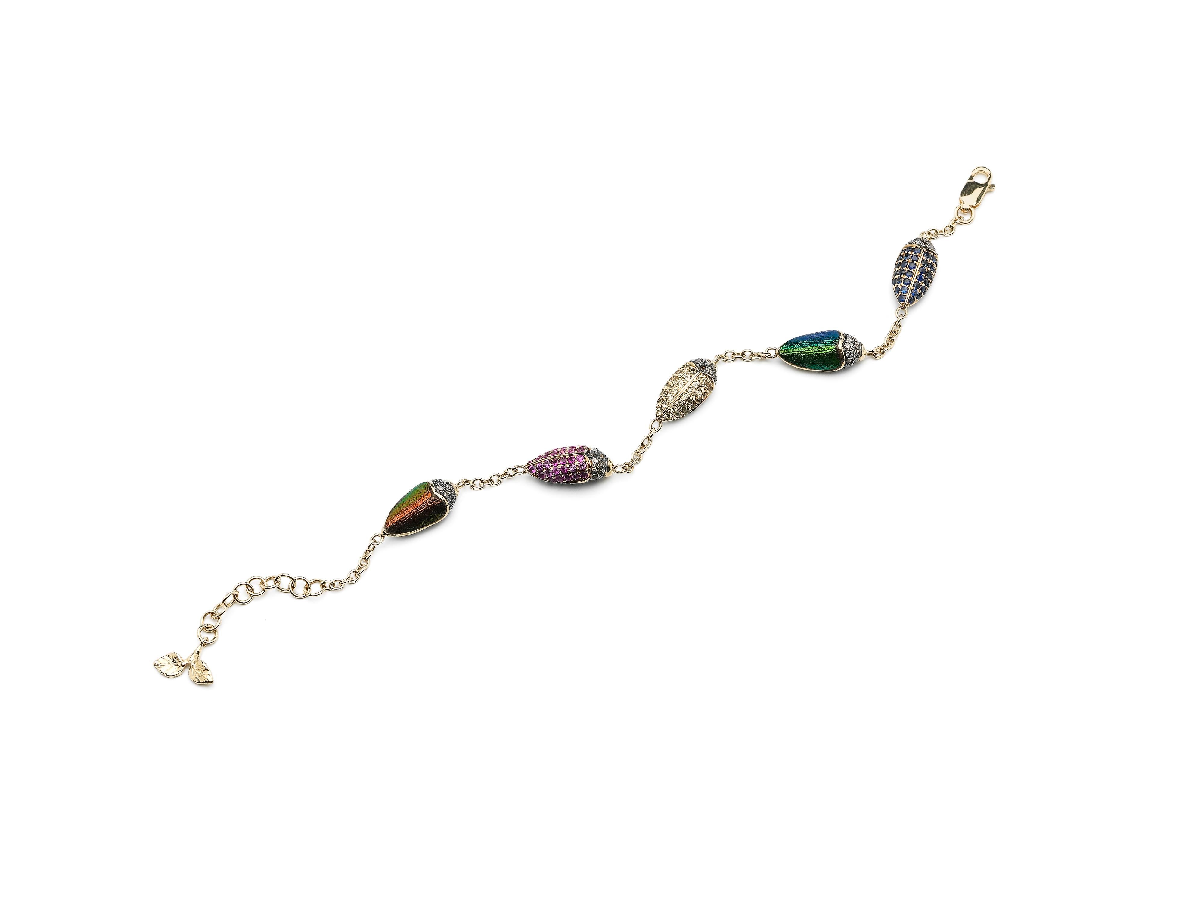 Five scarabs sit like dazzling charms on this 18k yellow gold and sterling silver bracelet. The scarabs shown here are set with real scarab wings, brown diamonds, blue sapphires, and tsavorites, but the design can be personalised so it’s unique to