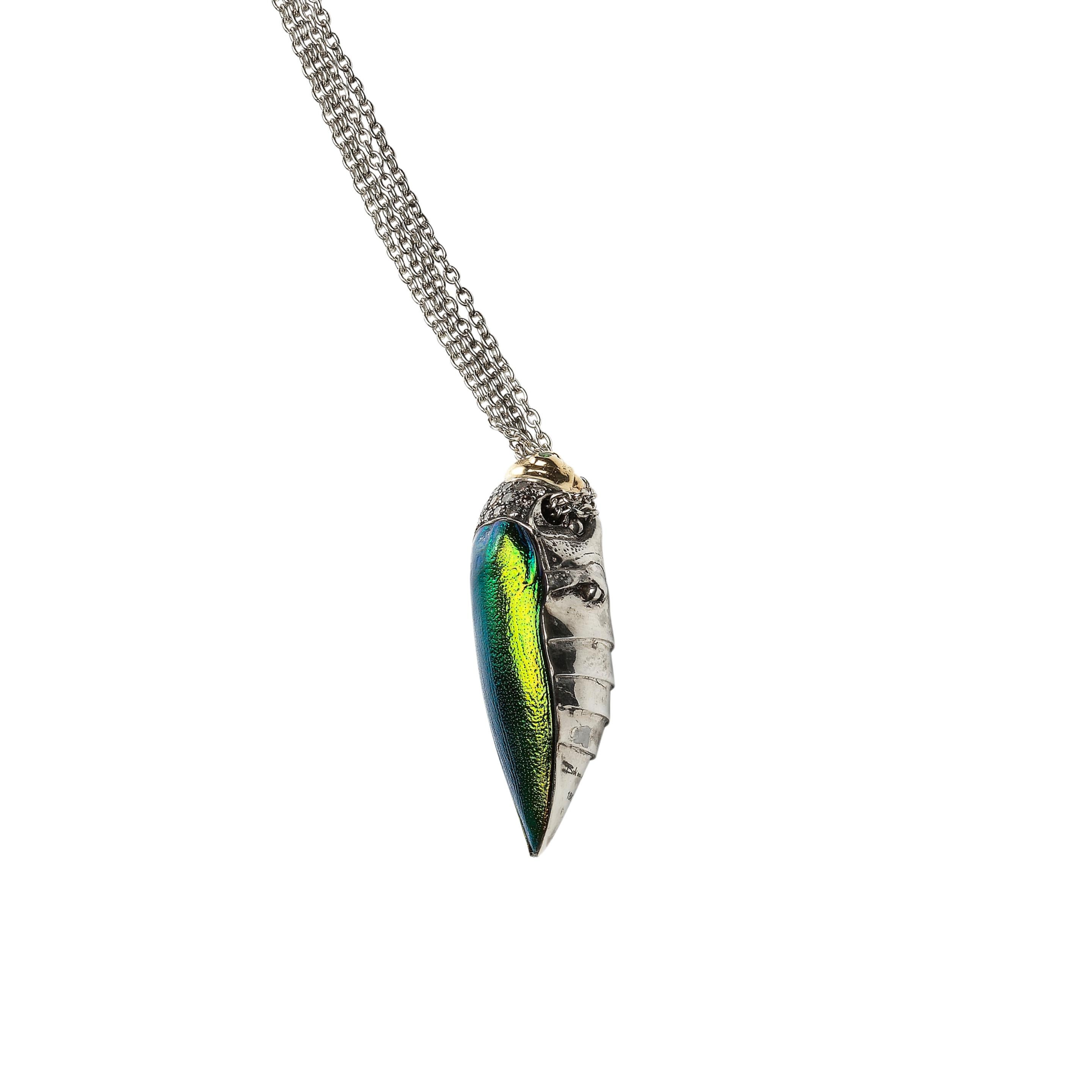
A single scarab beetle sits on this striking pendant necklace. Designed with a sterling silver body and 18k yellow gold head, the beetle is embellished with brown diamonds and a real scarab wing in iridescent tones of green and yellow.

Materials: