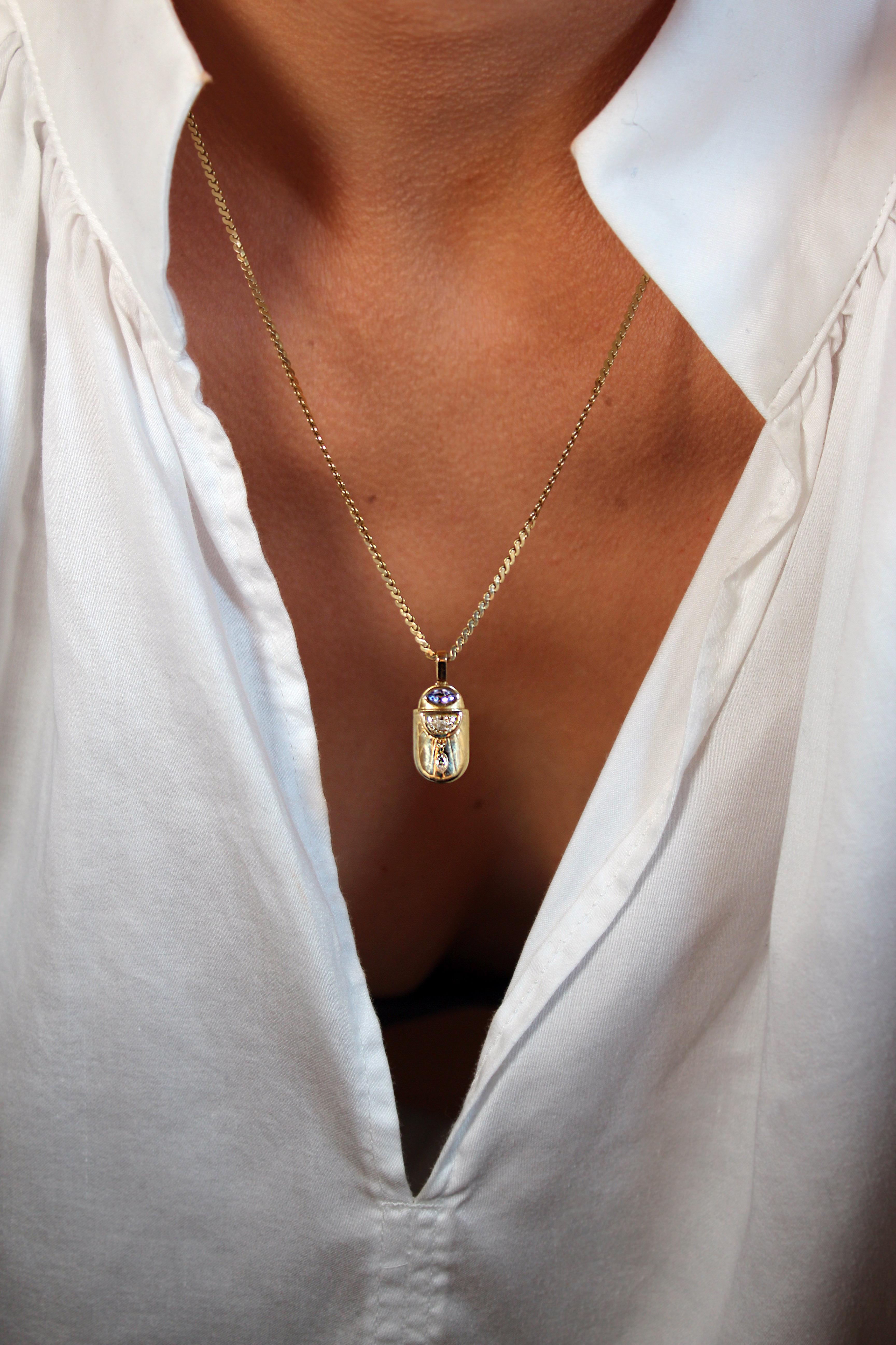 The form of a golden scarab, synonymous with the solar cycle in ancient Egypt, is the basis of this elegant and playful pendant. Sunrays run engraved along its gleaming back, above which sits a half moon-shaped lab diamond, and a marquise tanzanite