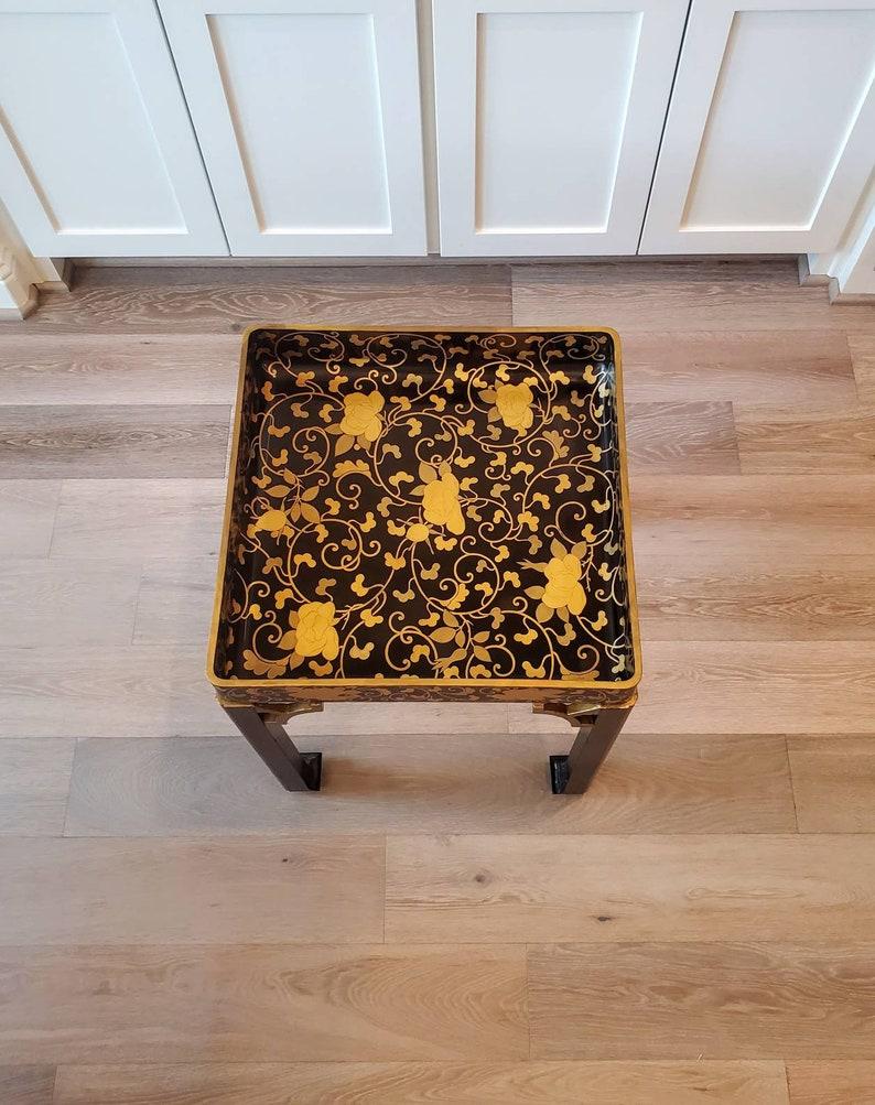 A rare 17th century ebonized Japanese lacquered tray with original gilt decoration, featuring trailing foliate vines and florals. The lacqueurware tray rests on a later stand with corner fretwork brackets, gilded accents, an X-form stretcher,