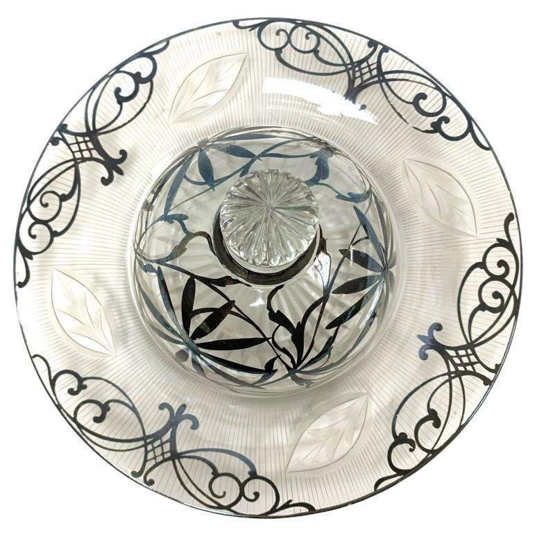 Vintage silver overlay cheese dish decorated with florals, twining vines and scrolls. The glass is clear however engraved on verso with cut navette form motifs and fine  engraved regimented lines along with a sun-ray cut finial.

Dimensions: 9 3/4