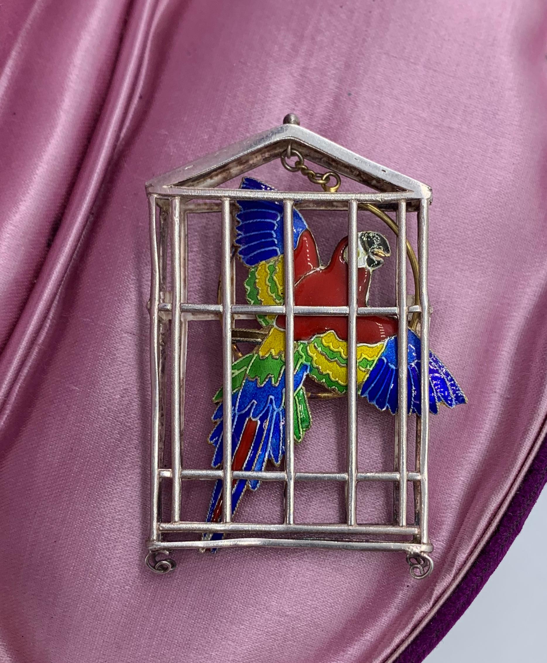 This is a delightful vibrant enamel and sterling silver of a Scarlet Macaw Parrot in a Cage Pendant.  The pendant is three-dimensional with the parrot floating freely within the cage and connected to the top of the cage with a chain!  I just love