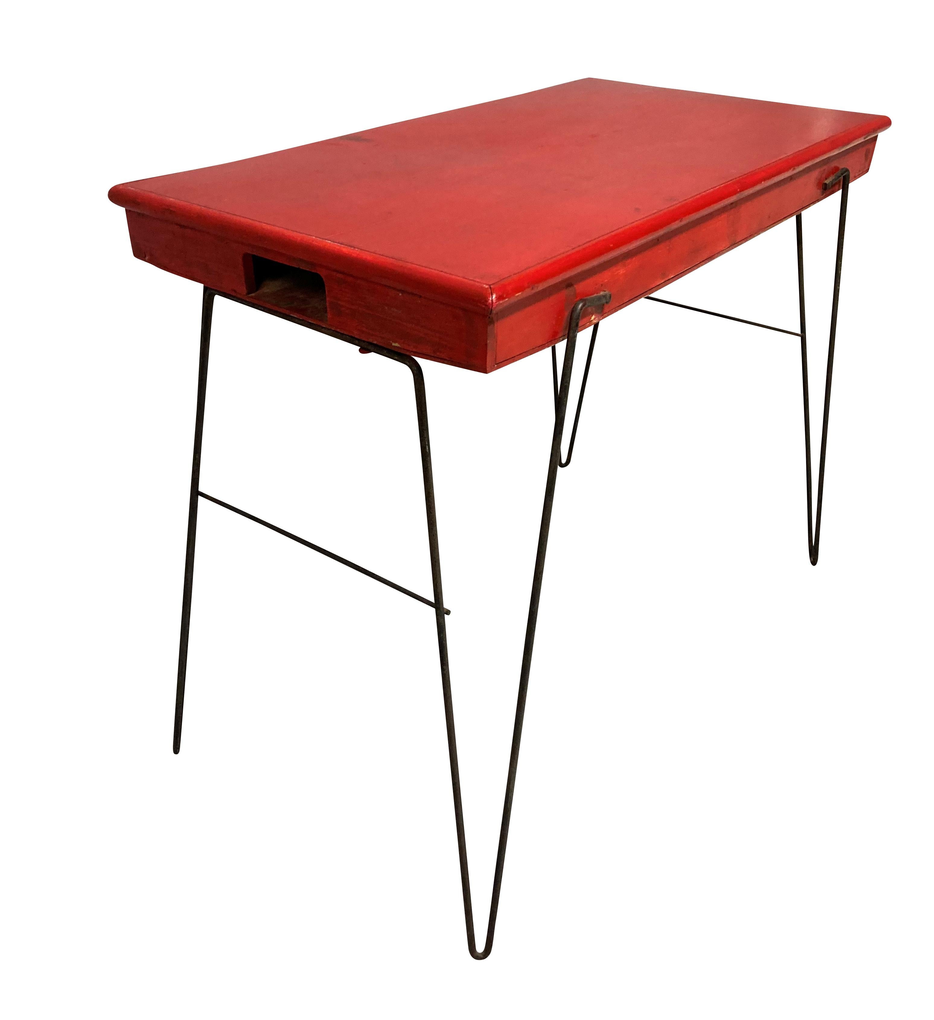 A French mid-century scarlet painted folding table, on tapering iron legs.