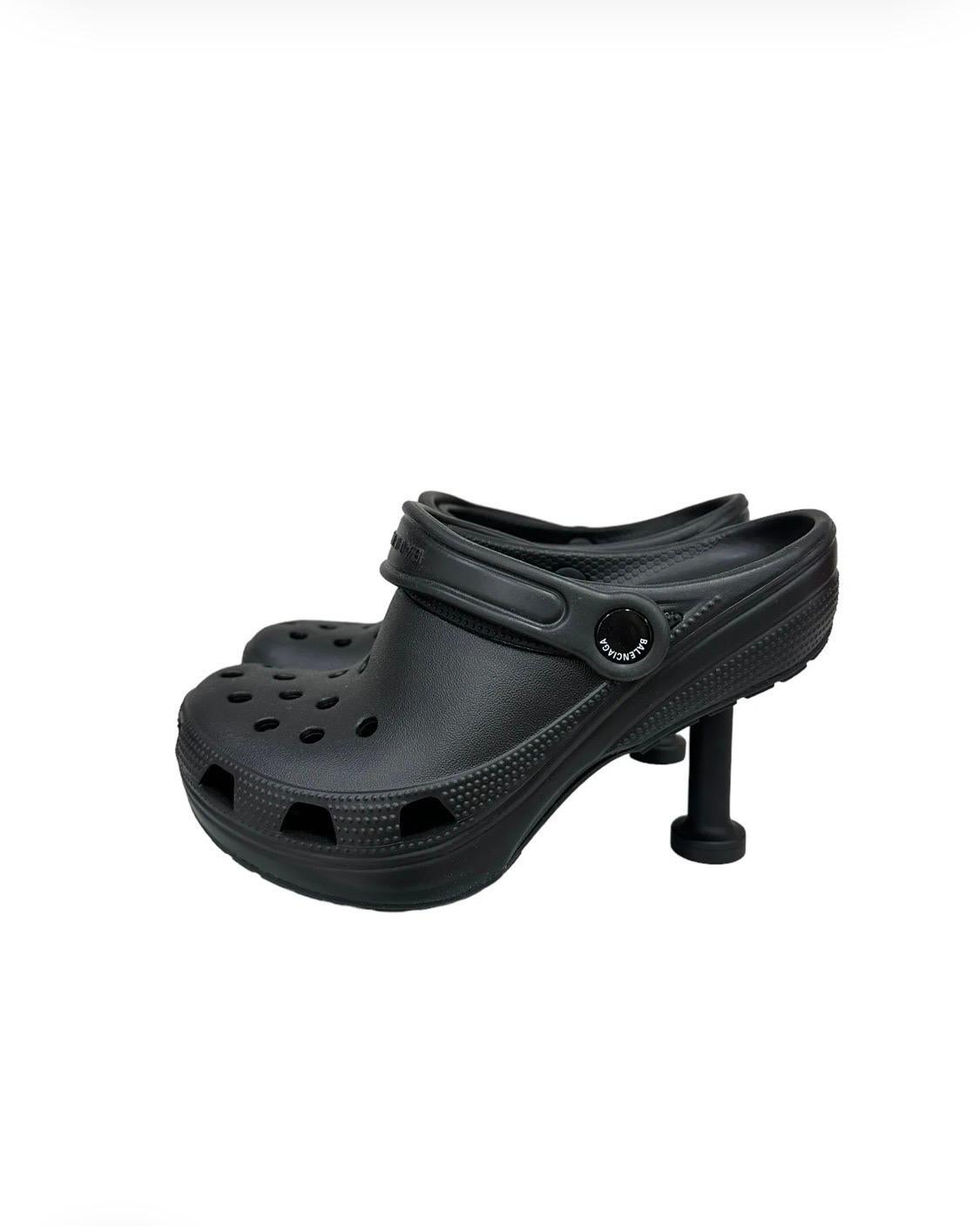 Pump Crocs Madame firmate Balenciaga x Crocs, collezione Clones Limited Edition, realizzata in gomma nera con hardware nero. Presenta una punta arrotondata con un tacco di 8 centimetri. Sulla parte posteriore è dotata di una fascetta con logo
