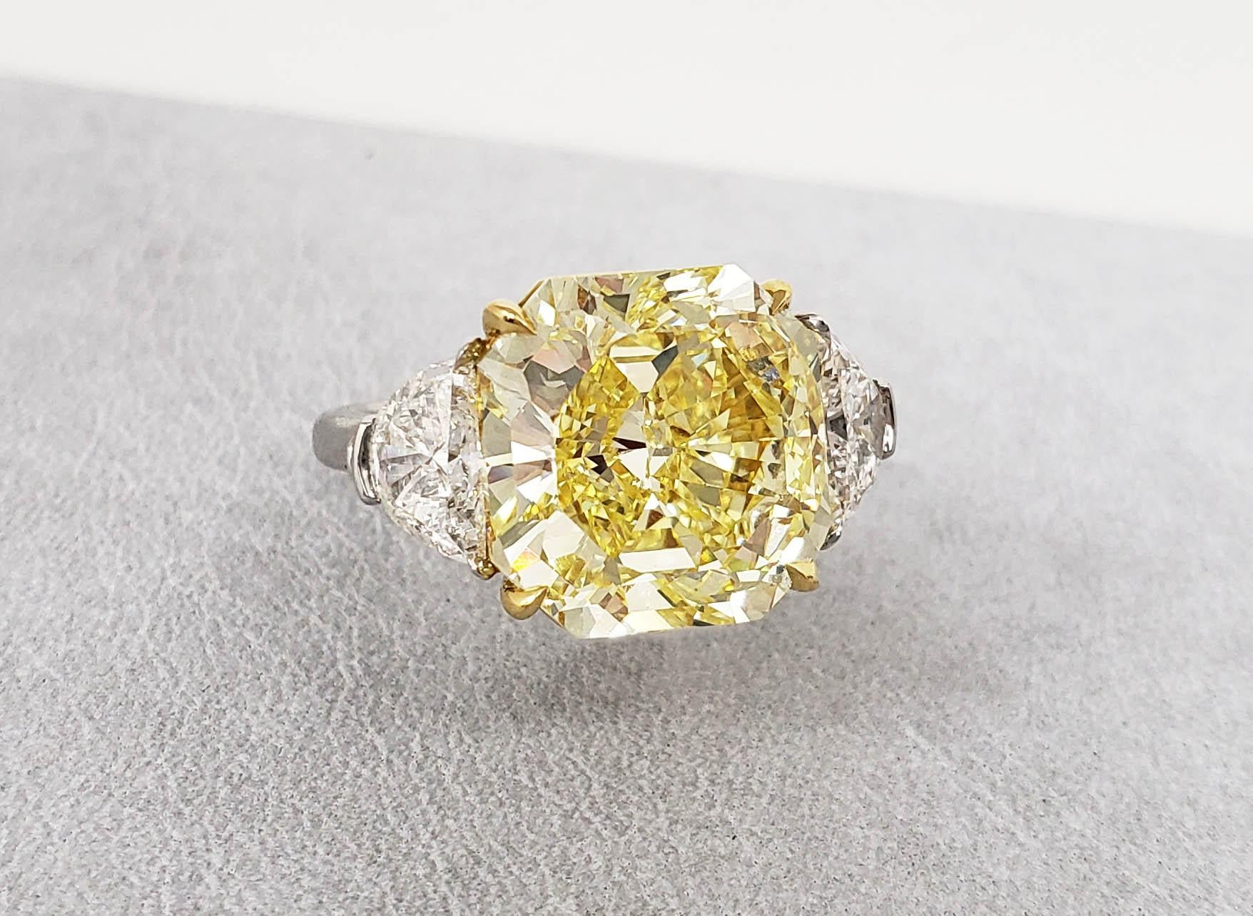 De la maison SCARSELLI, ce spectaculaire diamant de 10,05 carats de couleur Fancy Intense Yellow Radiant Cut est certifié sans défaut par le GIA et est serti d'une paire de diamants demi-lune blancs de couleur F-G et de pureté VS+.  

Cette bague