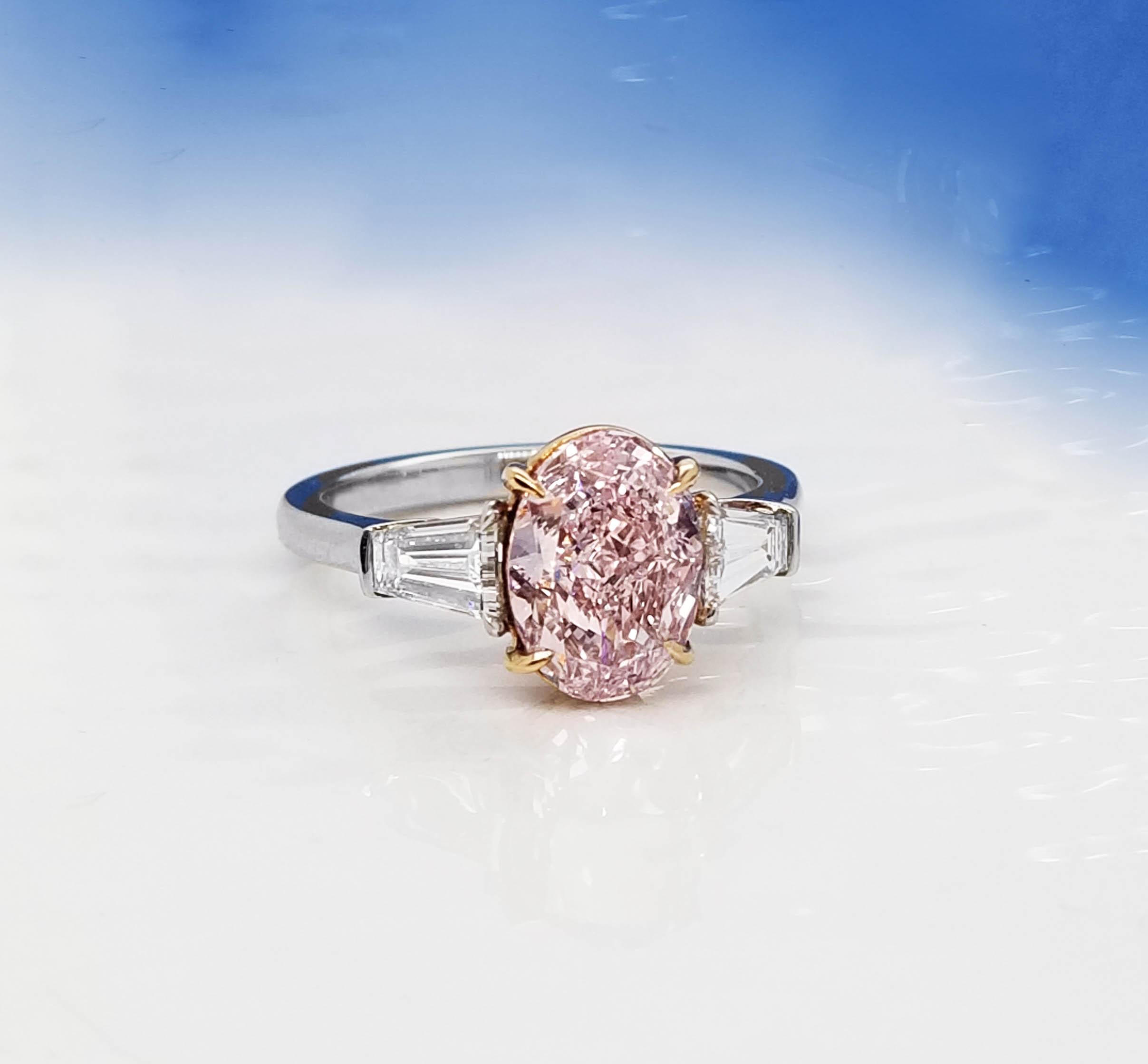 Provenant de SCARSELLI, une maison de diamants de couleur fantaisie de renommée mondiale, ce rare diamant ovale de couleur rose pourpre 2+ est de pureté VVS1 et est flanqué de baguettes de diamants blancs en platine pour un look classique qui plaira