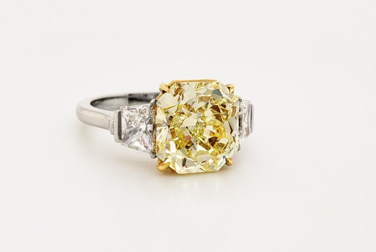 This SCARSELLI 4.01 carat Fancy Intense Yellow Radiant Cut Diamond Ring is  VVS2 clarity.   Flanking the center diamond are a pair of fine white brilliant cut trapezoid diamonds in platinum. The high quality of the diamonds and mounting are
