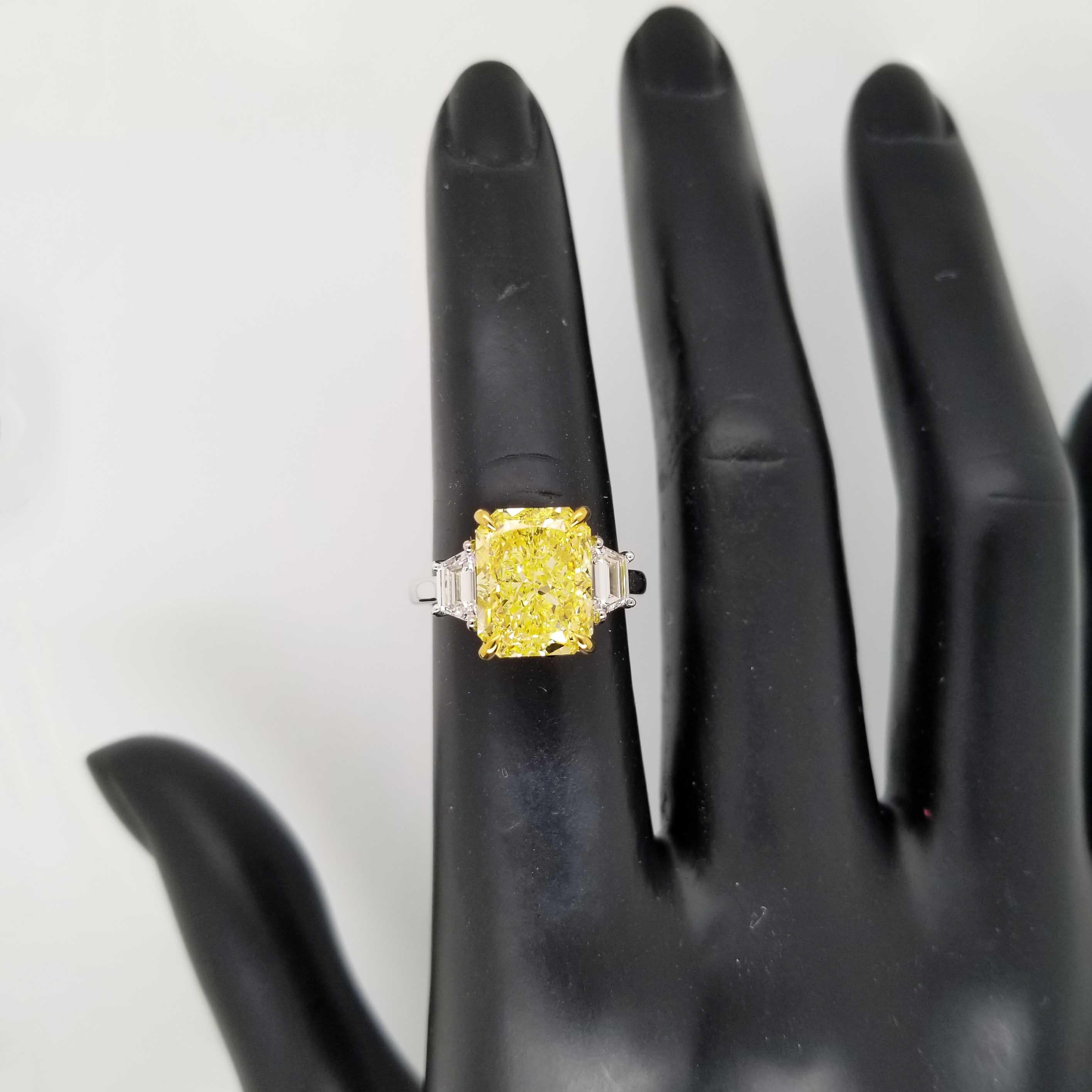 From SCARSELLI, this beautiful engagement ring features an over 5-carat Fancy Intense Yellow radiant cut diamond of VS2 clarity (see certificate picture for detailed stone's information) flanked by 2 trapezoids totaling 0.66ct (0.33 each). Handmade