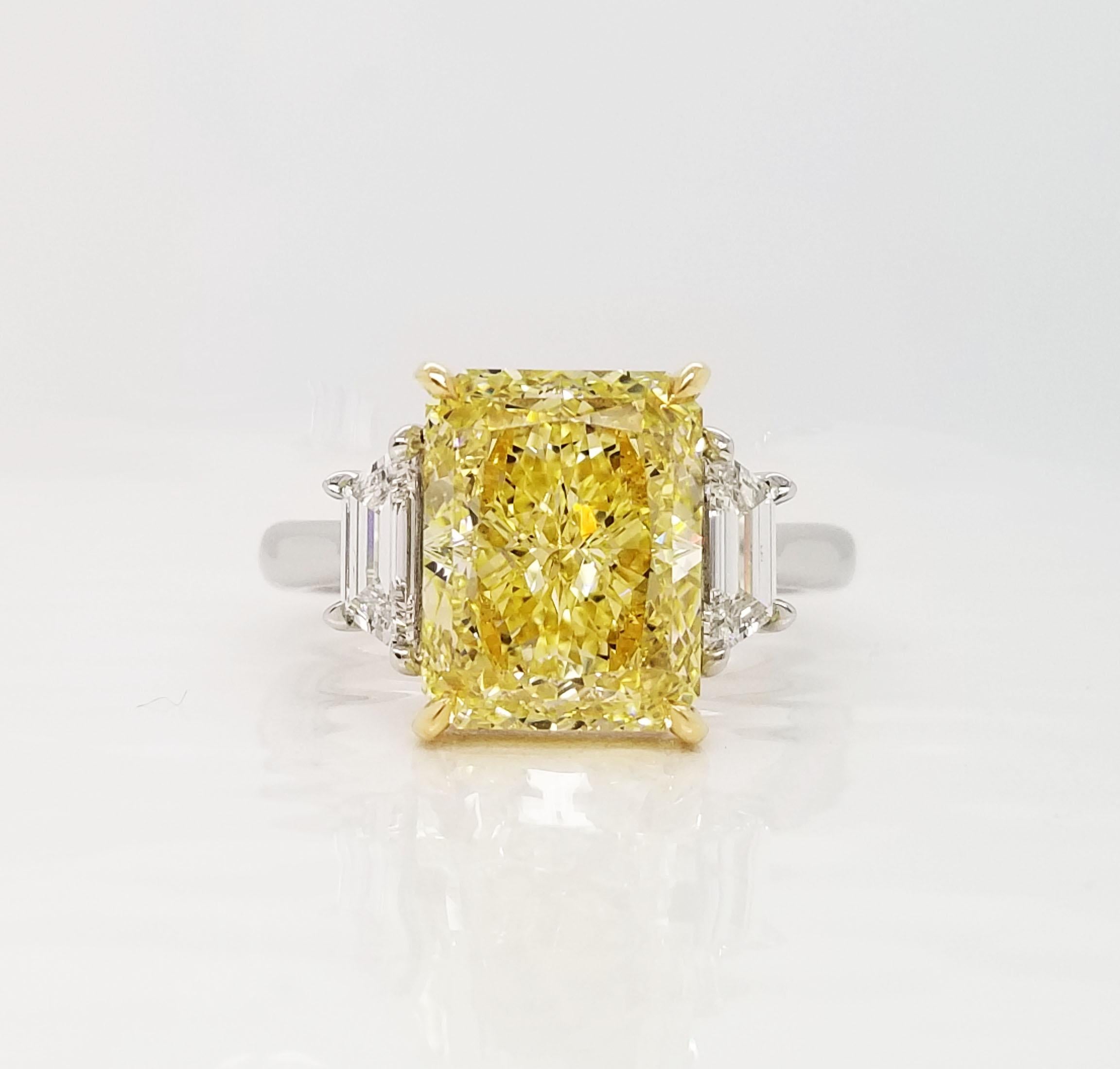 From SCARSELLI, this beautiful engagement ring features an over 5-carat Fancy Intense Yellow radiant cut diamond of VS2 clarity (see certificate picture for detailed stone's information) flanked by 2 trapezoids totaling 0.66ct (0.33 each). Handmade