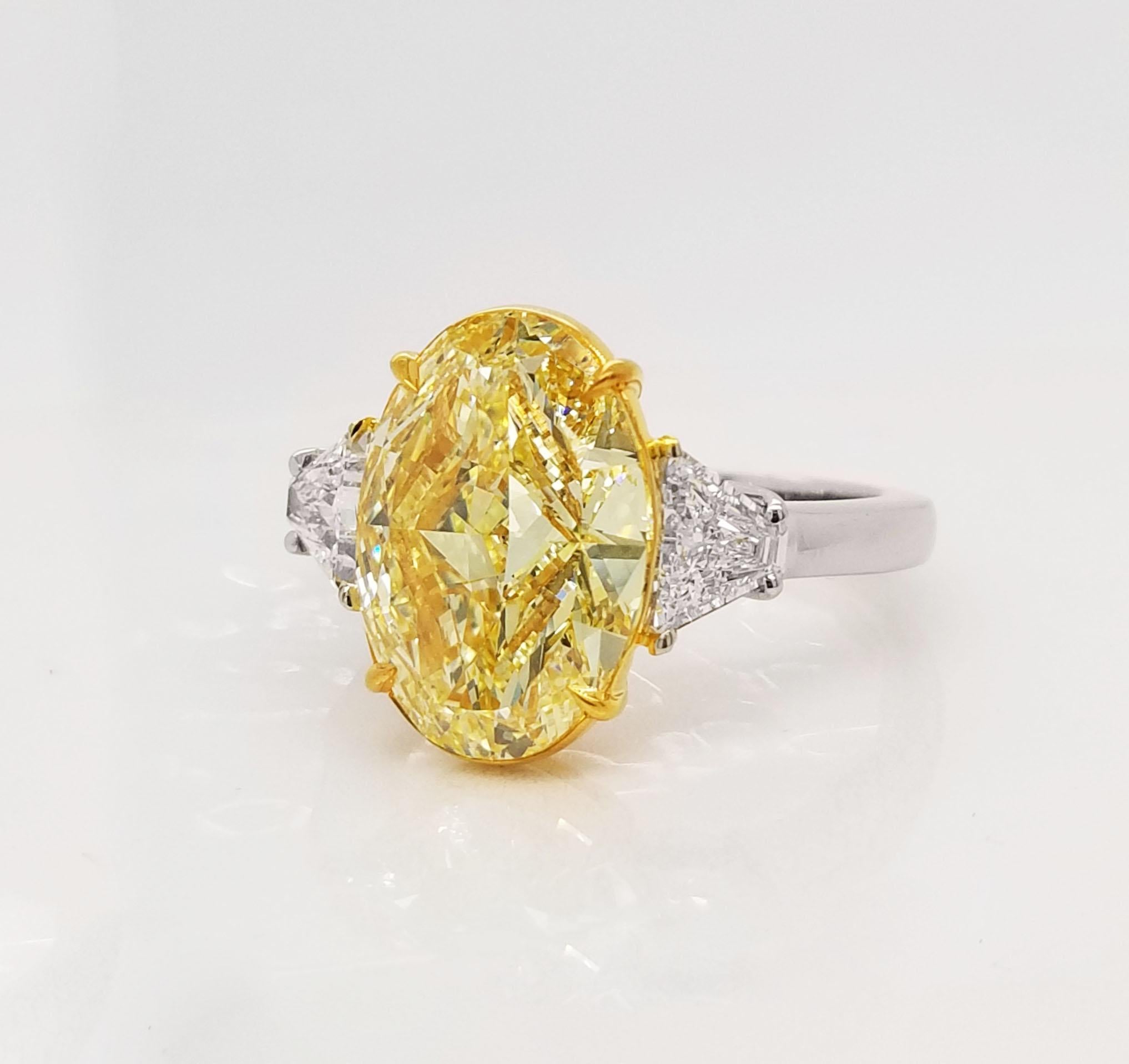 From SCARSELLI, this beautiful engagement ring features an over 5-carat Fancy Yellow Oval cut diamond (see certificate picture for detailed stone's information) flanked by 2 trapezoids totaling 0.66ct (0.33 each). Handmade setting in Platinum and