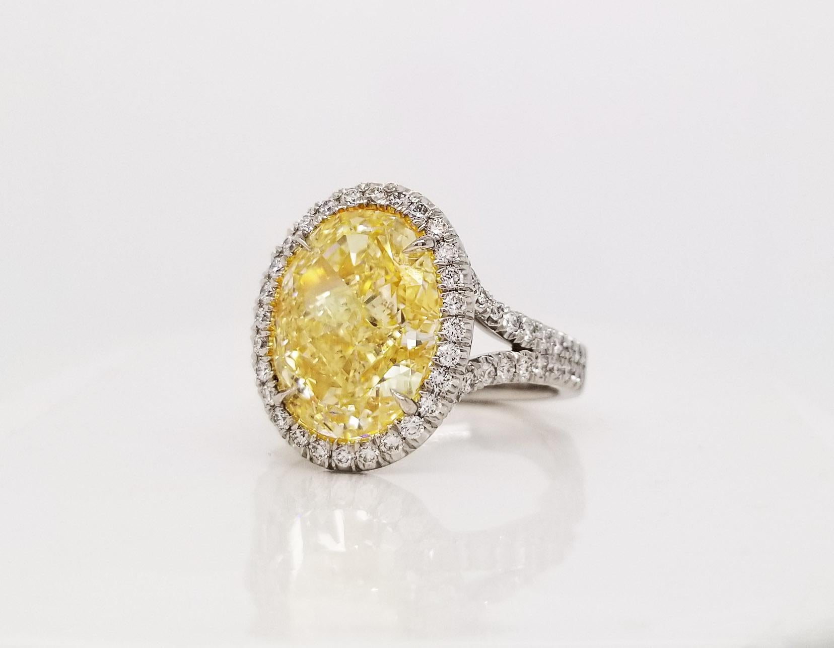 From SCARSELLI, a simply important ring featuring a 5 carats Fancy Light Yellow Oval cut diamond (GIA Certificate 5202491446 stone's detailed information) surrounded by 0.58 carats of white round brilliant diamonds in a coordinating handmade