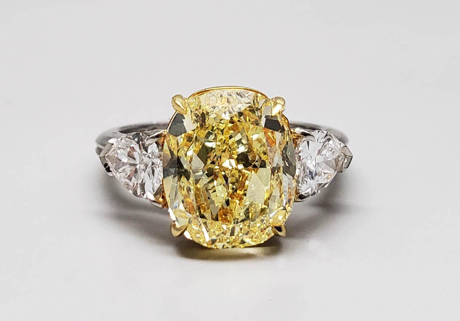 From SCARSELLI, this 5.68 carat Fancy Intense Yellow Cushion Cut Diamond is GIA Graded SI1 clarity.  The center diamond is flanked by a pair of pear shape white diamonds (2 = 1.10 carats)  F-G color VS+ clarity.  This ring is the most gorgeous of