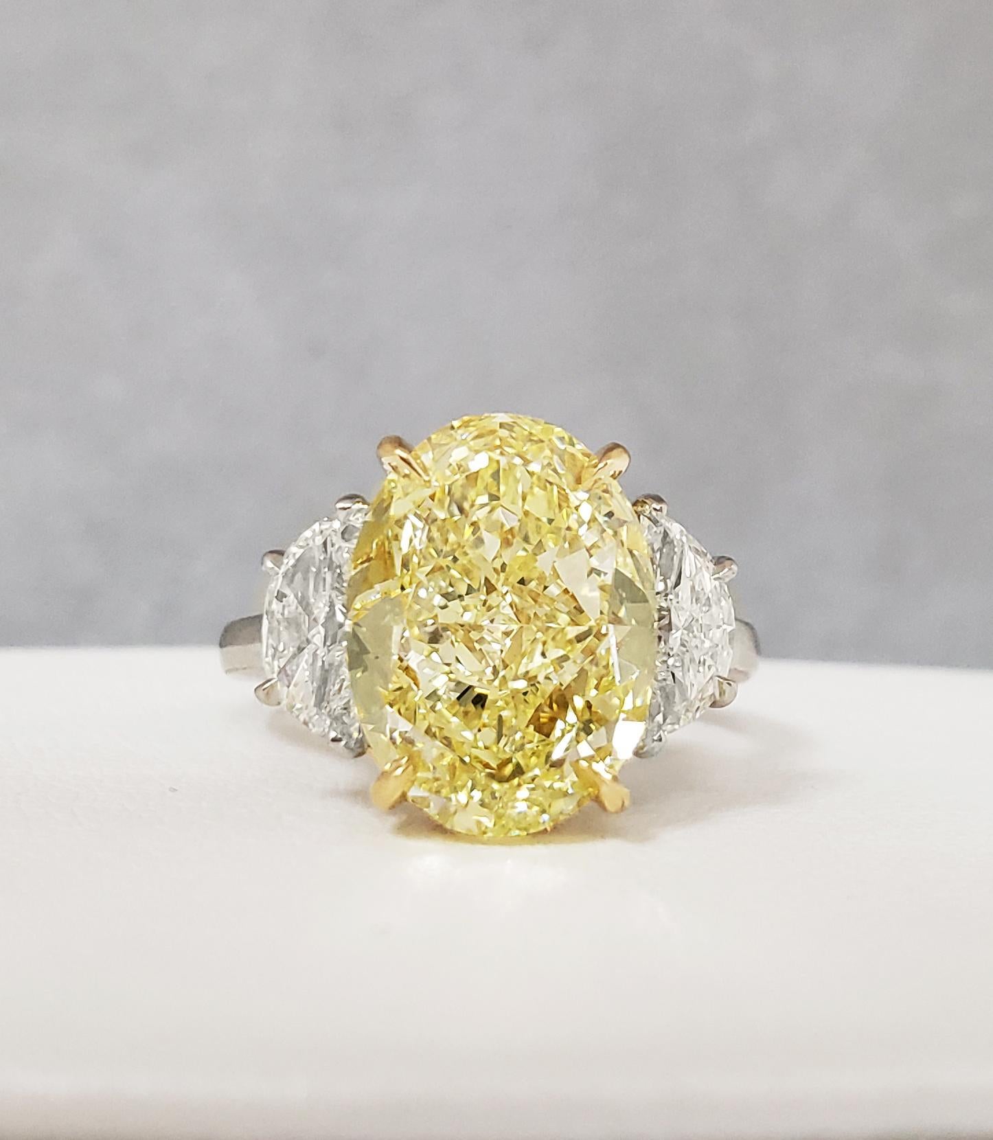 Scarselli's Classic Ring features a 6+ carat Fancy Yellow Oval Diamond with GIA certificate (see certificate picture for details of the stone). The center diamond is accompanied by two white half-moon cut diamonds, H color VS1 clarity 1.13 total