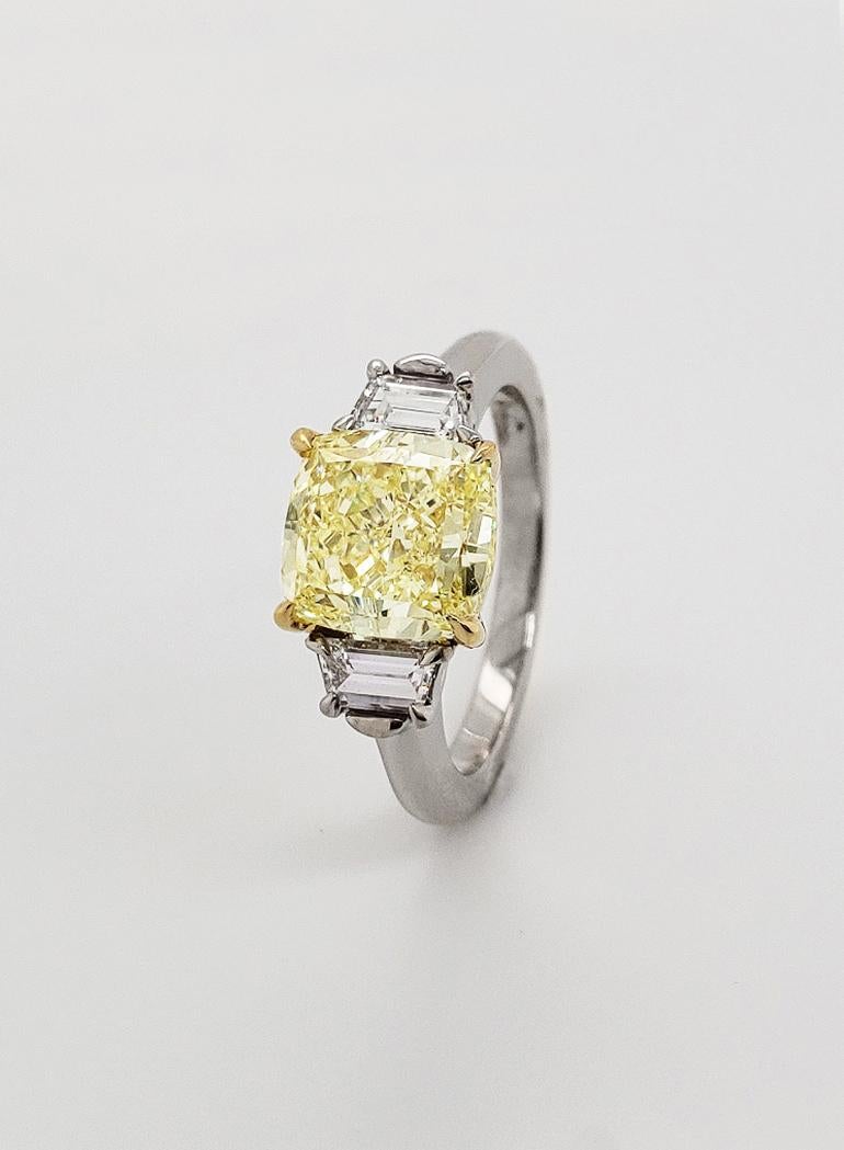 A 3.01 Cushion Cut, Natural Fancy Light Yellow Diamond Engagement Ring, GIA-Certified, flanked by .43 carats of white trapezoid diamonds, on an 18k Yellow Gold and Platinum band. With VVS2 Clarity, the center stone of this engagement ring is