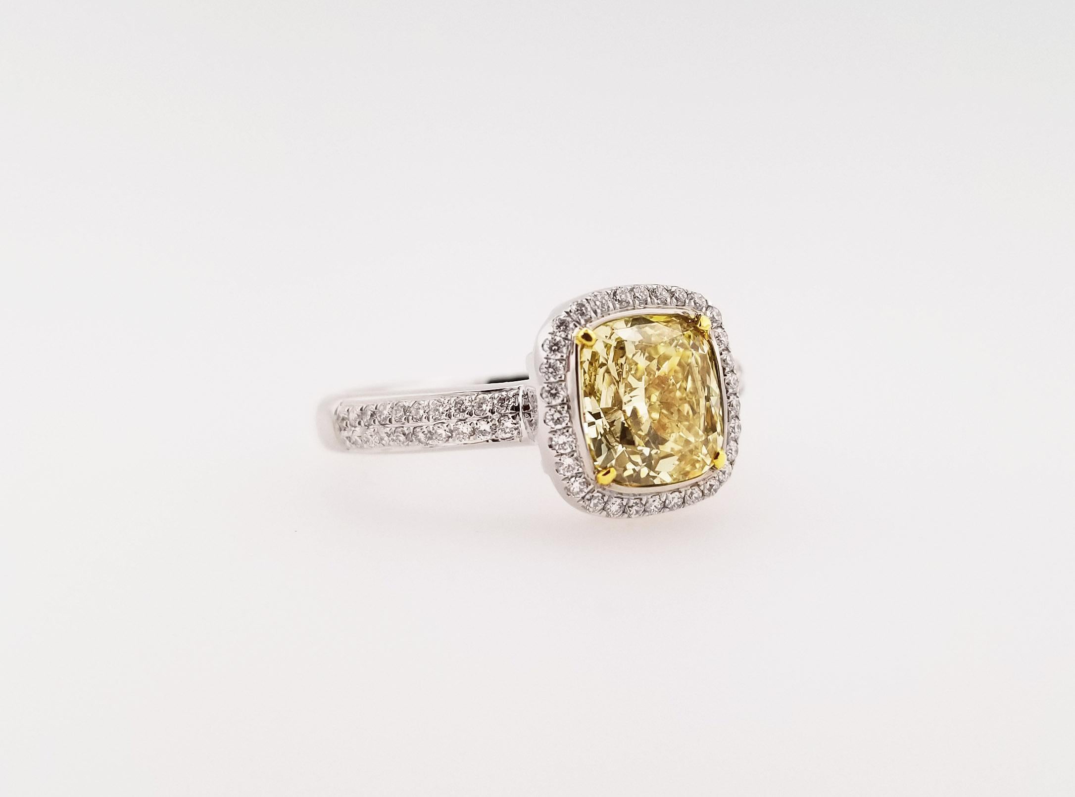 2.01 Carat Cushion-Cut Fancy Light Yellow GIA-Certified Diamond Engagement Ring from Scarselli. An SI1 center stone is flanked by a row of white round diamonds in a halo-setting, set upon an 18K White Gold ring. The side stones TCW is 0.26 carats